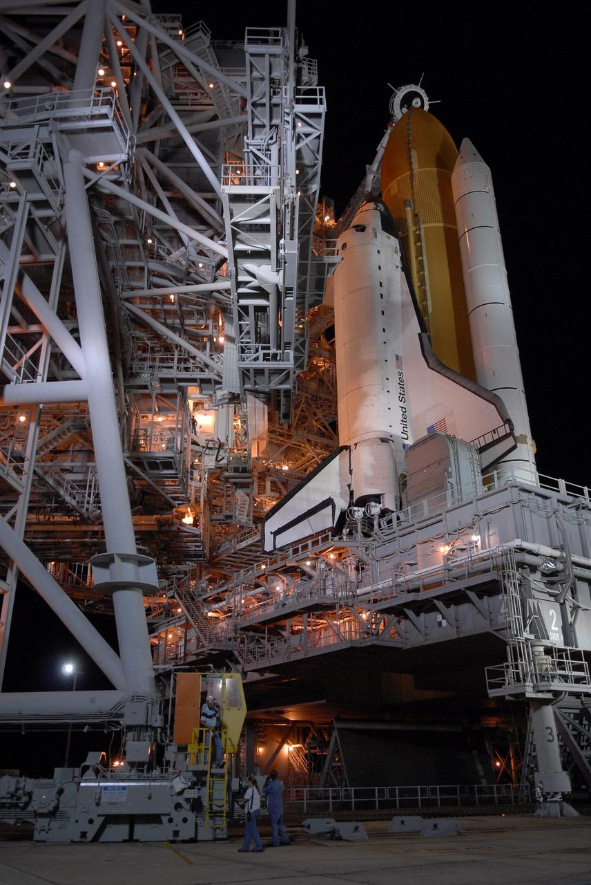 KENNEDY SPACE CENTER, FLA. --  Rollback of the rotating service structure, or RSS, begins on Launch Pad 39A, revealing Space Shuttle Atlantis, bathed in lights. Rollback is one of the milestones in preparation for the launch of mission STS-117 on June 8 and started at 10:56 p.m. EDT. The RSS provides protected access to the orbiter for changeout and servicing of payloads at the pad. The structure is supported by a rotating bridge that pivots about a vertical axis on the side of the pad's flame trench. The hinge column rests on the pad surface and is braced to the fixed service structure.  Support for the outer end of the bridge is provided by two eight-wheel, motor-driven trucks that move along circular twin rails installed flush with the pad surface. The track crosses the flame trench on a permanent bridge. The RSS is 102 feet long, 50 feet wide and 130 feet high. The structure has orbiter access platforms at five levels to provide access to the payload bay while the orbiter is being serviced in the RSS. Each platform has independent extendable planks that can be arranged to conform to a payload's configuration. This mission is the 118th shuttle flight and the 21st U.S. flight to the International Space Station and will deliver and install the S3/S4 truss segment, deploy a set of solar arrays and prepare them for operation.  Photo credit: NASA/Kim Shiflett