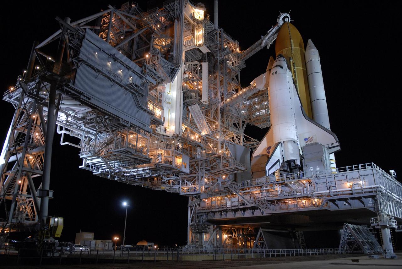KENNEDY SPACE CENTER, FLA. --  Following rollback of the rotating service structure, or RSS, on Launch Pad 39A, Space Shuttle Atlantis stands bathed in lights atop a mobile launch platform. Rollback is one of the milestones in preparation for the launch of mission STS-117 on June 8. Rollback started at 10:56 p.m. and was complete at 11:34 p.m EDT. The RSS, the massive structure to the left of the shuttle, provides protected access to the orbiter for changeout and servicing of payloads at the pad. The structure is supported by a rotating bridge that pivots about a vertical axis on the side of the pad's flame trench. The hinge column rests on the pad surface and is braced to the fixed service structure.  Support for the outer end of the bridge is provided by two eight-wheel, motor-driven trucks that move along circular twin rails installed flush with the pad surface. The track crosses the flame trench on a permanent bridge. The RSS is 102 feet long, 50 feet wide and 130 feet high. The structure has orbiter access platforms at five levels to provide access to the payload bay while the orbiter is being serviced in the RSS. Each platform has independent extendable planks that can be arranged to conform to a payload's configuration. This mission is the 118th shuttle flight and the 21st U.S. flight to the International Space Station and will deliver and install the S3/S4 truss segment, deploy a set of solar arrays and prepare them for operation.  Photo credit: NASA/Kim Shiflett
