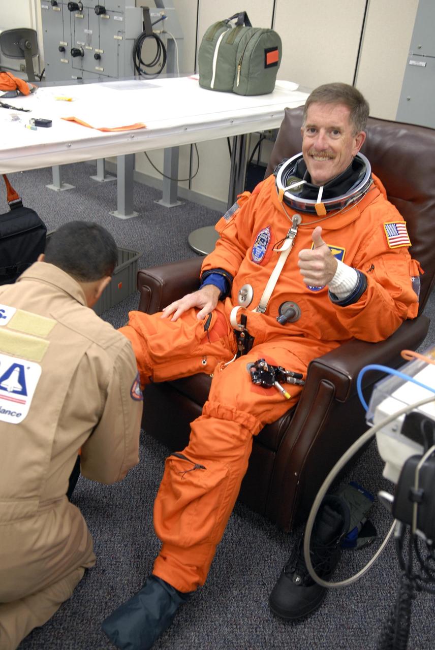 KENNEDY SPACE CENTER, FLA. --  The crew members of mission STS-117 are suiting up for a launch attempt at 7:38 p.m. EDT from Launch Pad 39A aboard Space Shuttle Atlantis. Pictured here is Mission Specialist James Reilly, who gets help with his boot.  Reilly is making his third shuttle flight. The shuttle is delivering a new segment to the starboard side of the International Space Station's backbone, known as the truss. Three spacewalks are planned to install the S3/S4 truss segment, deploy a set of solar arrays and prepare them for operation. STS-117 is the 118th space shuttle flight, the 21st flight to the station, the 28th flight for Atlantis and the first of four flights planned for 2007.    Photo credit: NASA/Kim Shiflett