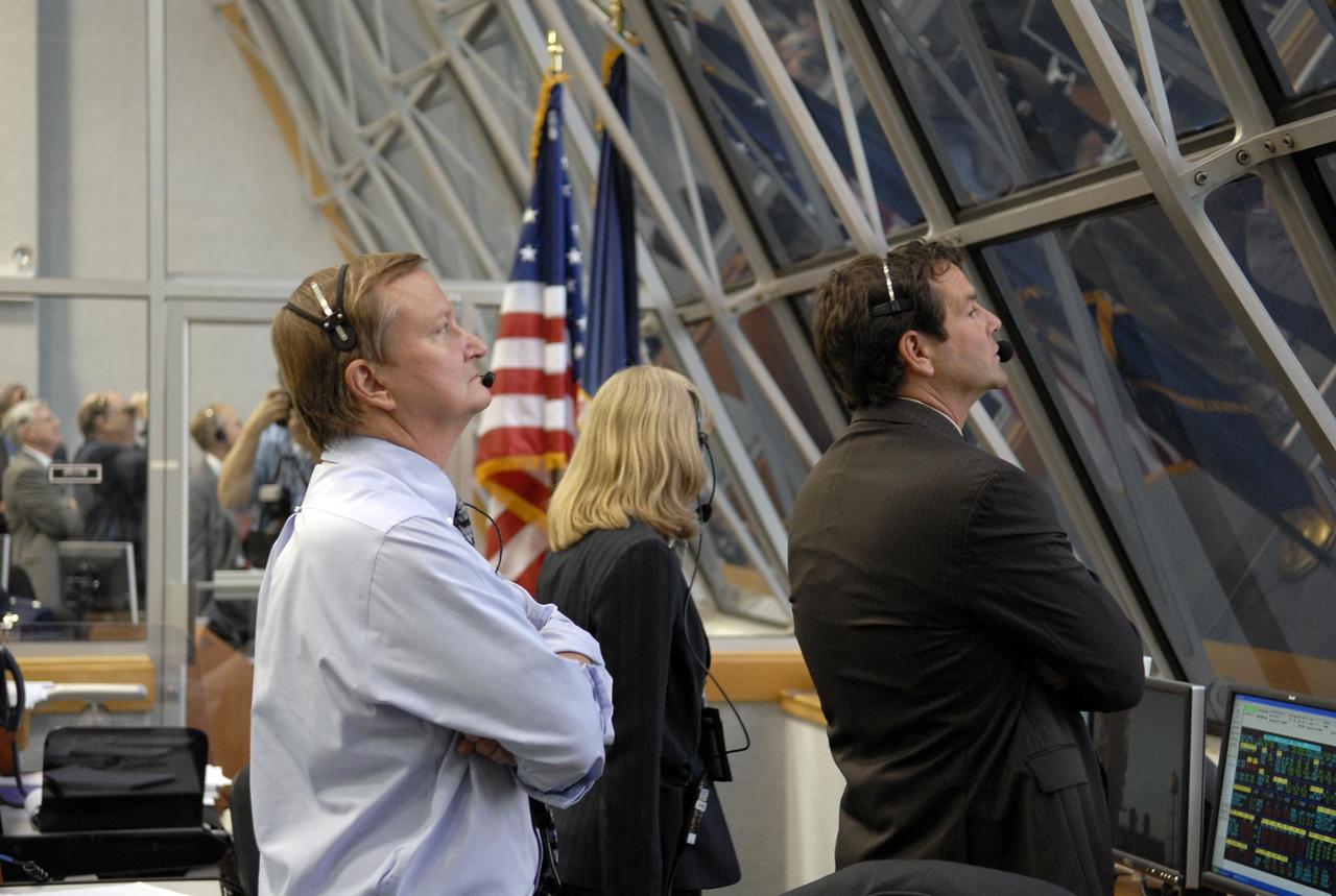 KENNEDY SPACE CENTER, FLA. -- Through the windows of the Launch Control Center, Shuttle Launch Director Mike Leinbach (left) watches the near-perfect launch of Space Shuttle Atlantis on mission STS-117 to the International Space Station. In front of him are Angie Brewer, NASA flow director for Atlantis, and Doug Lyons, assistant launch director. Liftoff from Launch Pad 39A was on-time at 7:38:04 p.m. EDT. The shuttle is delivering a new segment to the starboard side of the International Space Station's backbone, known as the truss. Three spacewalks are planned to install the S3/S4 truss segment, deploy a set of solar arrays and prepare them for operation. STS-117 is the 118th space shuttle flight, the 21st flight to the station, the 28th flight for Atlantis and the first of four flights planned for 2007. Photo credit: NASA/Kim Shiflett