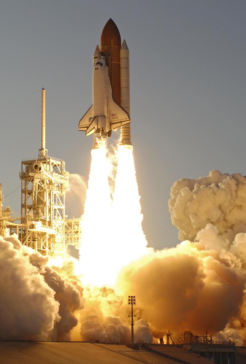 KENNEDY SPACE CENTER, FLA. --  Columns of fire flow from the solid rocket boosters launching Space Shuttle Atlantis on mission STS-117 while masses of smoke and steam billow across Launch Pad 39A.   Atlantis passes the fixed service structure at left, topped by the 80-foot-tall lightning mast.  Liftoff was on-time at 7:38:04 p.m. EDT. The shuttle is delivering a new segment to the starboard side of the International Space Station's backbone, known as the truss. Three spacewalks are planned to install the S3/S4 truss segment, deploy a set of solar arrays and prepare them for operation. STS-117 is the 118th space shuttle flight, the 21st flight to the station, the 28th flight for Atlantis and the first of four flights planned for 2007.   Photo courtesy of Nikon/Scott Andrews