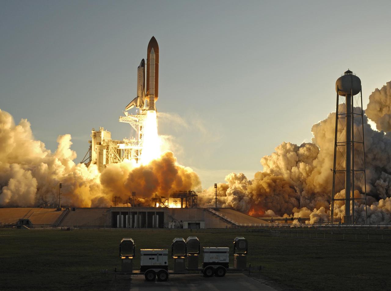KENNEDY SPACE CENTER, FLA. --  Smoke and steam billow across Launch Pad 39A as Space Shuttle Atlantis, trailing columns of fire from the solid rocket boosters, hurtles into the sky on mission STS-117 to the International Space Station.  At right is the water tank that provides the deluge over the mobile launcher platform for sound suppression during liftoff.  Liftoff was on-time at 7:38:04 p.m. EDT.The shuttle is delivering a new segment to the starboard side of the International Space Station's backbone, known as the truss. Three spacewalks are planned to install the S3/S4 truss segment, deploy a set of solar arrays and prepare them for operation. STS-117 is the 118th space shuttle flight, the 21st flight to the station, the 28th flight for Atlantis and the first of four flights planned for 2007.   Photo courtesy of Nikon/Scott Andrews