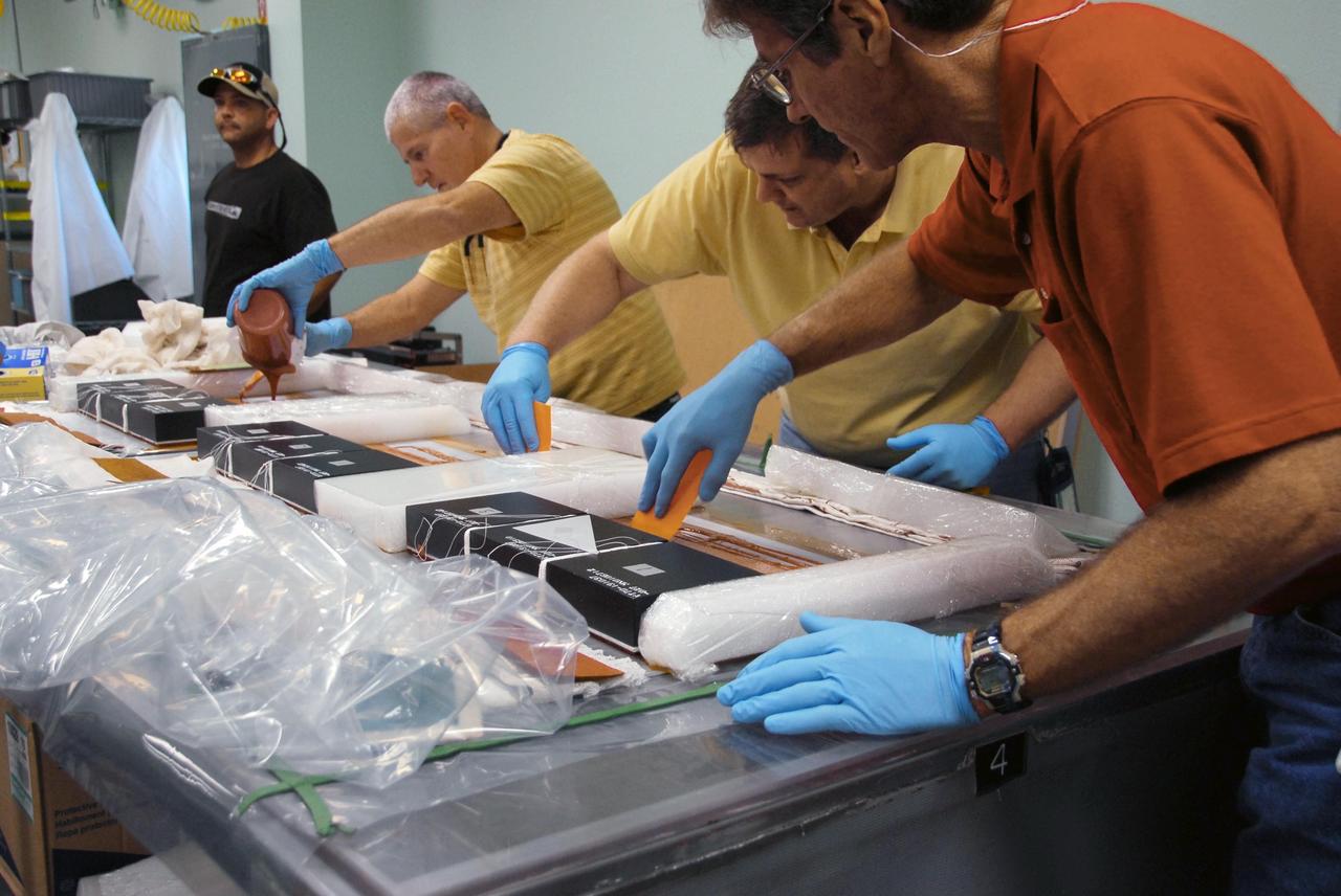 KENNEDY SPACE CENTER, FLA. --   United Space Alliance employees prepare test articles to be used in wind tunnel testing by NASA to collect data for analysis of the detached Flexible Insulation Blanket, or FIB, on Atlantis.   A tear occurred in an area of the OMS pod on Atlantis during launch of mission STS-117 on June 8, 2007.  The test articles each feature three tiles (Low Temperature Reusable Surface Insulation, or LRSI) affixed next to two FIB blankets, simulating the thermal protection system set-up on Atlantis' OMS pod in the vicinity of the in-flight anomaly.  These test articles will be flown to Texas the morning of June 14.  The TPS team at KSC has also provided a total of 22 FIB samples for other testing and analysis. Repair is under consideration following testing at KSC and Houston.  Photo credit: NASA/Amanda Diller