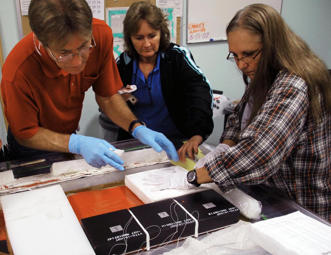 KENNEDY SPACE CENTER, FLA. --   United Space Alliance employees prepare test articles to be used in wind tunnel testing by NASA to collect data for analysis of the detached Flexible Insulation Blanket, or FIB, on Atlantis.  A tear occurred in an area of the OMS pod on Atlantis during launch of mission STS-117 on June 8, 2007.  The test articles each feature three tiles (Low Temperature Reusable Surface Insulation, or LRSI) affixed next to two FIB blankets, simulating the thermal protection system set-up on Atlantis' OMS pod in the vicinity of the in-flight anomaly.  These test articles will be flown to Texas the morning of June 14.  The TPS team at KSC has also provided a total of 22 FIB samples for other testing and analysis. Repair is under consideration following testing at KSC and Houston.  Photo credit: NASA/Amanda Diller