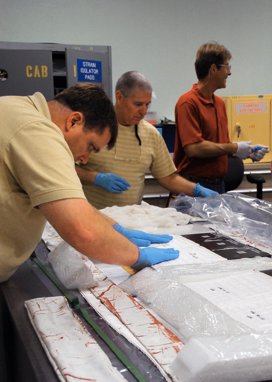 KENNEDY SPACE CENTER, FLA. --   United Space Alliance employees prepare test articles to be used in wind tunnel testing by NASA to collect data for analysis of the detached Flexible Insulation Blanket, or FIB, on Atlantis.  A tear occurred in an area of the OMS pod on Atlantis during launch of mission STS-117 on June 8, 2007.  The test articles each feature three tiles (Low Temperature Reusable Surface Insulation, or LRSI) affixed next to two FIB blankets, simulating the thermal protection system set-up on Atlantis' OMS pod in the vicinity of the in-flight anomaly.  These test articles will be flown to Texas the morning of June 14.  The TPS team at KSC has also provided a total of 22 FIB samples for other testing and analysis. Repair is under consideration following testing at KSC and Houston.  Photo credit: NASA/Amanda Diller