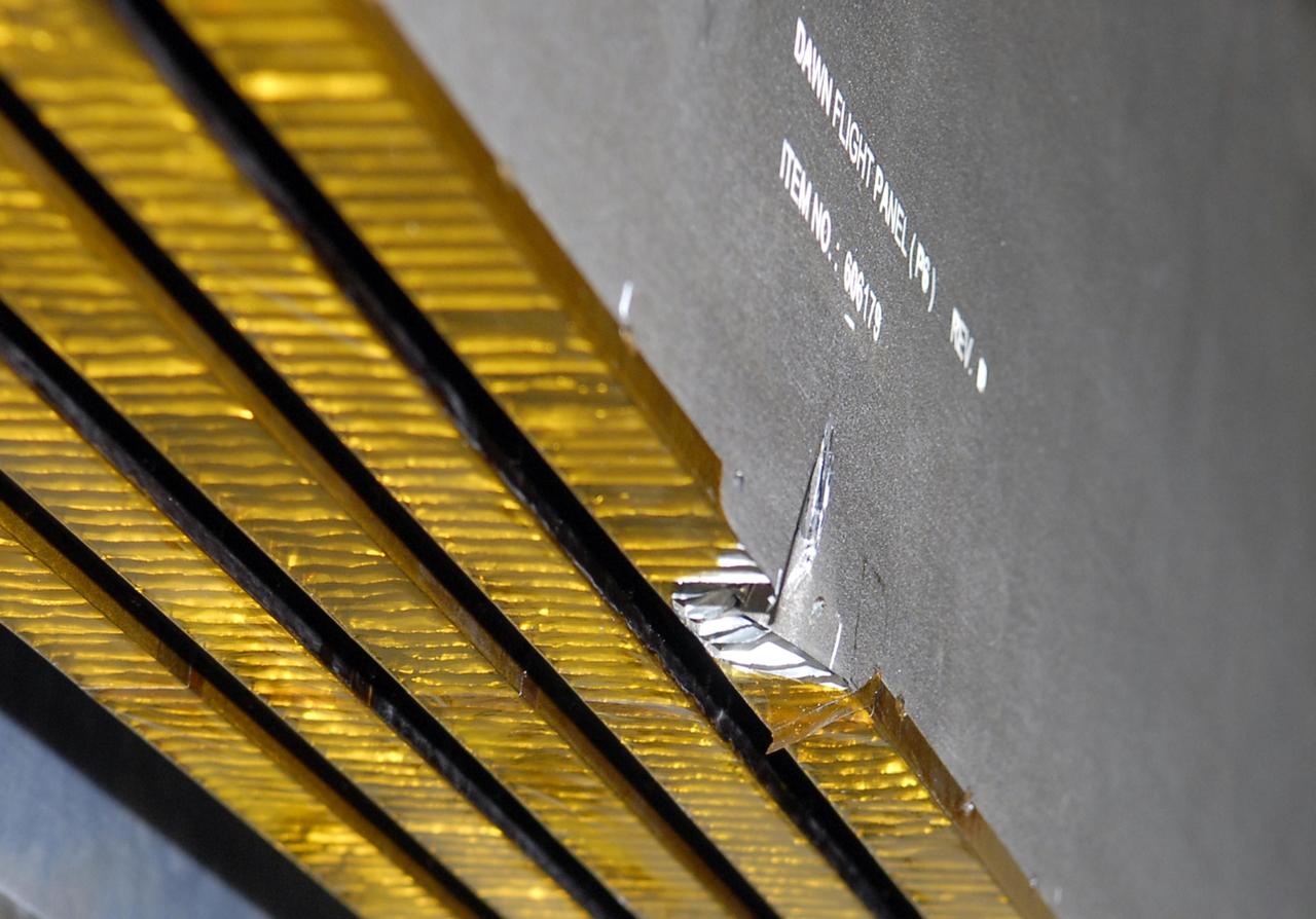 KENNEDY SPACE CENTER, FLA. -- This closeup shows the slight damage done by a technician's tool to the back of a solar array panel on June 11 during a procedure to prepare the Dawn spacecraft for spin-balance testing. Dawn's goal is to characterize the conditions and processes of the solar system's earliest epoch by investigating in detail the largest protoplanets that have remained intact since their formations: asteroid Vesta and the dwarf planet Ceres. They reside in the extensive zone between Mars and Jupiter together with many other smaller bodies, called the asteroid belt. Dawn is scheduled to launch July 7. Photo credit: NASA/Kim Shiflett