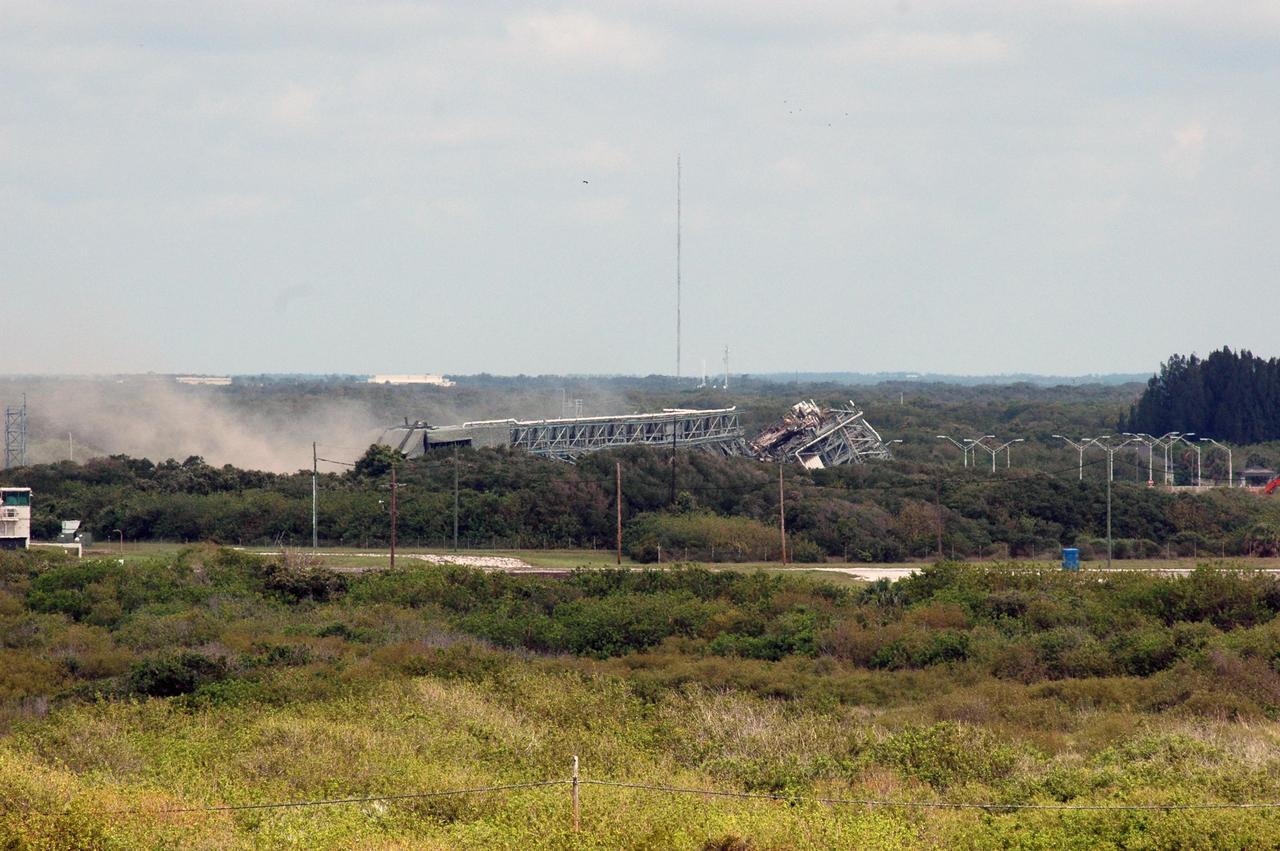 KENNEDY SPACE CENTER, FLA. --  After the dust settles at Space Launch Complex 36 on Cape Canaveral Air Force Station, the ruins of the 209-foot-tall mobile service tower on Pad 39-B are visible. The tower is one of two that were identified for demolition. The old towers are being toppled as part of the ongoing project to demolish the historic site to prevent corrosion from becoming a safety concern.   A majority of the steel will be recycled and the rest will be taken to the landfill at CCAFS.  Complex 36 was the birthplace of NASA's planetary launch program.  It was built for the Atlas/Centaur development program and was operated under NASA's sponsorship until the late 1980s. Complex 36 hosted many historic missions over the years including Surveyor that landed on the moon and Mariner that orbited Mars and included one to Mercury.  Two of the most historic launches were the Pioneer 10 and 11 space probes that were launched to Jupiter and are now outside of the solar system in interstellar space.  Also, the historic Pioneer Venus spacecraft included an orbiter and a set of probes that were dispatched to the surface.  While Launch Complex 36 is gone, the Atlas/Centaur rocket continues to be launched as the Atlas V from Complex 41. Photo credit: NASA/Charisse Nahser