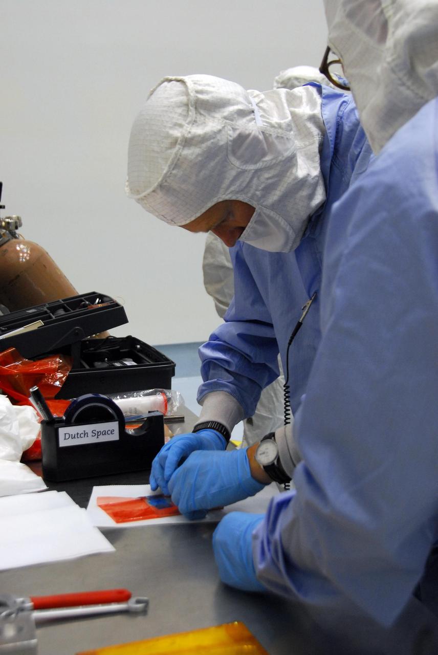 KENNEDY SPACE CENTER, FLA. --At Astrotech, engineers from Dutch Space prepare materials to make repairs on the slight damage done by a technician's tool to the back of a solar array panel of the Dawn spacecraft on June 11 during a procedure to prepare Dawn for spin-balance testing. The size of the affected area is about 2.5 inches by 2 inches. There is no impact to the launch date of July 7. Dawn's goal is to characterize the conditions and processes of the solar system's earliest epoch 4.5 billion years ago by investigating in detail two of the largest asteroids, Ceres and Vesta. They reside between Mars and Jupiter in the asteroid belt. Photo credit: NASA/George Shelton