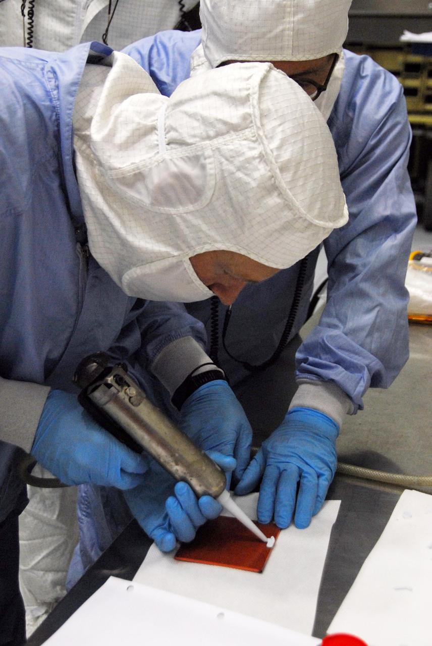 KENNEDY SPACE CENTER, FLA. -- At Astrotech, engineers from Dutch Space prepare materials to make repairs on the slight damage done by a technician's tool to the back of a solar array panel of the Dawn spacecraft on June 11 during a procedure to prepare Dawn for spin-balance testing. The size of the affected area is about 2.5 inches by 2 inches. There is no impact to the launch date of July 7. Dawn's goal is to characterize the conditions and processes of the solar system's earliest epoch 4.5 billion years ago by investigating in detail two of the largest asteroids, Ceres and Vesta. They reside between Mars and Jupiter in the asteroid belt. Photo credit: NASA/George Shelton