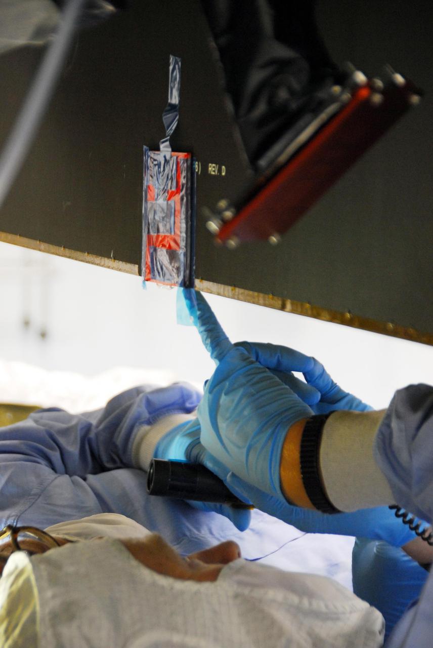 KENNEDY SPACE CENTER, FLA. -- At Astrotech, engineers from Dutch Space are making repairs on the slight damage done by a technician's tool to the back of a solar array panel of the Dawn spacecraft on June 11 during a procedure to prepare Dawn for spin-balance testing. The size of the affected area is about 2.5 inches by 2 inches. There is no impact to the launch date of July 7. Dawn's goal is to characterize the conditions and processes of the solar system's earliest epoch 4.5 billion years ago by investigating in detail two of the largest asteroids, Ceres and Vesta. They reside between Mars and Jupiter in the asteroid belt. Photo credit: NASA/George Shelton