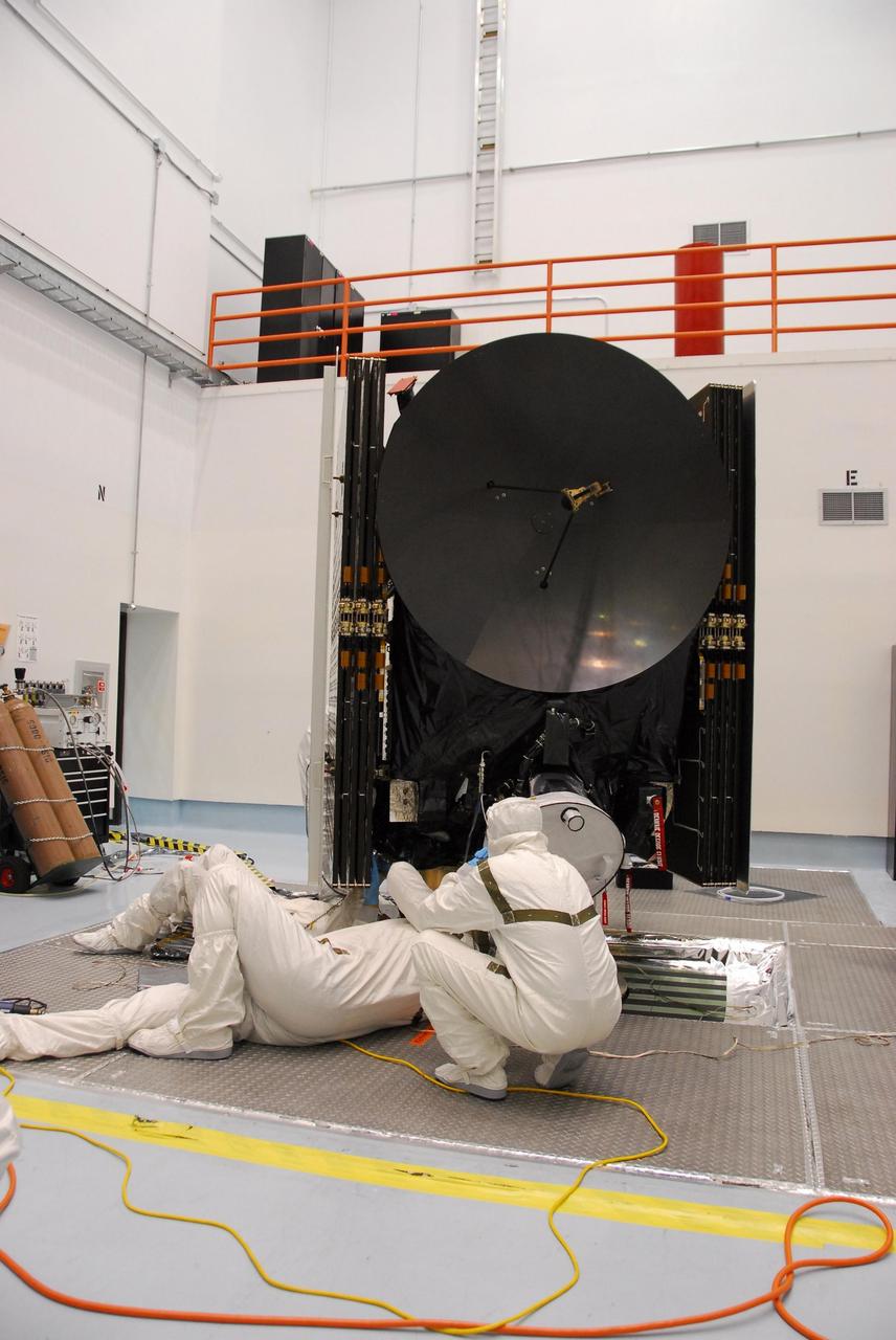 KENNEDY SPACE CENTER, FLA. -- At Astrotech, engineers from Dutch Space lie underneath the Dawn spacecraft to examine the repairs under process on damage made to the solar array panel. The damage occurred on June 11 from a technician's tool during a procedure to prepare Dawn for spin-balance testing. The size of the affected area is about 2.5 inches by 2 inches. There is no impact to the launch date of July 7. Dawn's goal is to characterize the conditions and processes of the solar system's earliest epoch 4.5 billion years ago by investigating in detail two of the largest asteroids, Ceres and Vesta. They reside between Mars and Jupiter in the asteroid belt. Photo credit: NASA/George Shelton