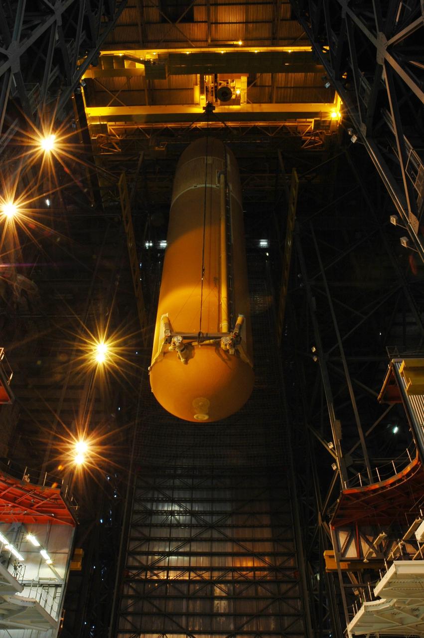 KENNEDY SPACE CENTER, FLA. -- Inside the Vehicle Assembly Building, the external tank for Endeavour is lowered toward the mobile launcher platform for mating with the solid rocket boosters. Endeavour is currently targeted for rollover to the VAB July 5. In the background, at right, is one of the boosters. Endeavour is the designated orbiter for mission STS-118, targeted for launch on Aug. 9 to the International Space Station. The mission will continue space station construction by delivering a third starboard truss segment, S5, as well as carrying the external stowage platform 3. Photo credit: NASA/Amanda Diller