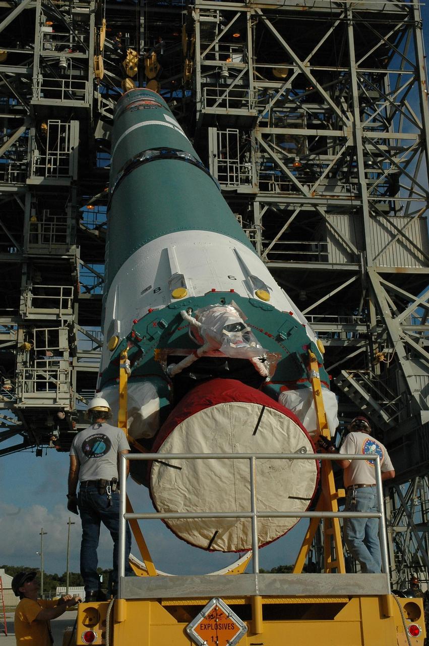 KENNEDY SPACE CENTER, FLA. -- On Launch Pad 17-A at Cape Canaveral Air Force Station, the first stage of a Delta II rocket is raised off the transporter beneath the mobile service tower. The rocket is the launch vehicle for the Phoenix spacecraft, targeted for launch on Aug. 3 heading for Mars. Phoenix will land in icy soils near the north polar permanent ice cap of Mars and explore the history of the water in these soils and any associated rocks, while monitoring polar climate. Landing on Mars is planned in May 2008 on arctic ground where a mission currently in orbit, Mars Odyssey, has detected high concentrations of ice just beneath the top layer of soil. Photo credit: NASA/Amanda Diller