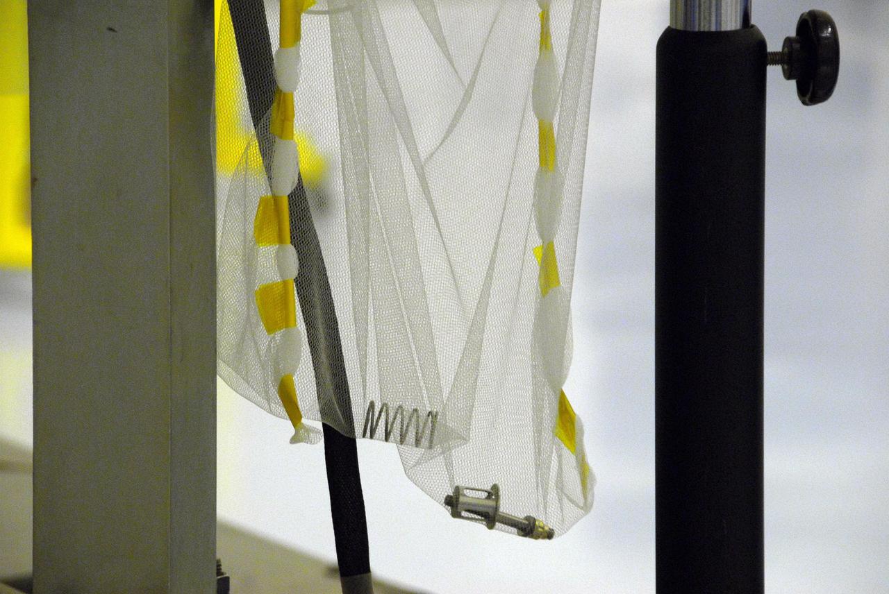 KENNEDY SPACE CENTER, FLA. -- In the Payload Hazardous Servicing Facility at Cape Canaveral Air Force Station, this mesh bag holds the spring and bolt from the test firing to deploy the solar panels on the Phoenix Mars Lander spacecraft. Phoenix will land in icy soils near the north polar permanent ice cap of Mars and explore the history of the water in these soils and any associated rocks, while monitoring polar climate. Landing on Mars is planned in May 2008 on arctic ground where a mission currently in orbit, Mars Odyssey, has detected high concentrations of ice just beneath the top layer of soil. Phoenix is scheduled to launch Aug. 3. Photo credit: NASA/George Shelton