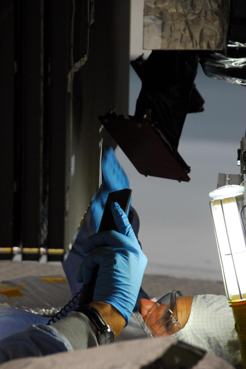 KENNEDY SPACE CENTER, FLA. -- At Astrotech, a Dutch Space technician repairs the damage to the lower edge of the solar array panel on the Dawn spacecraft. On June 11, during a procedure to prepare the Dawn spacecraft for spin-balance testing, the back of a solar array panel was slightly damaged by a technician's tool. The size of the affected area is about 2.5 inches by 2 inches. There is no impact to the launch date of July 7. Dawn's goal is to characterize the conditions and processes of the solar system's earliest epoch 4.5 billion years ago by investigating in detail two of the largest asteroids, Ceres and Vesta. They reside between Mars and Jupiter in the asteroid belt. Photo credit: NASA/George Shelton