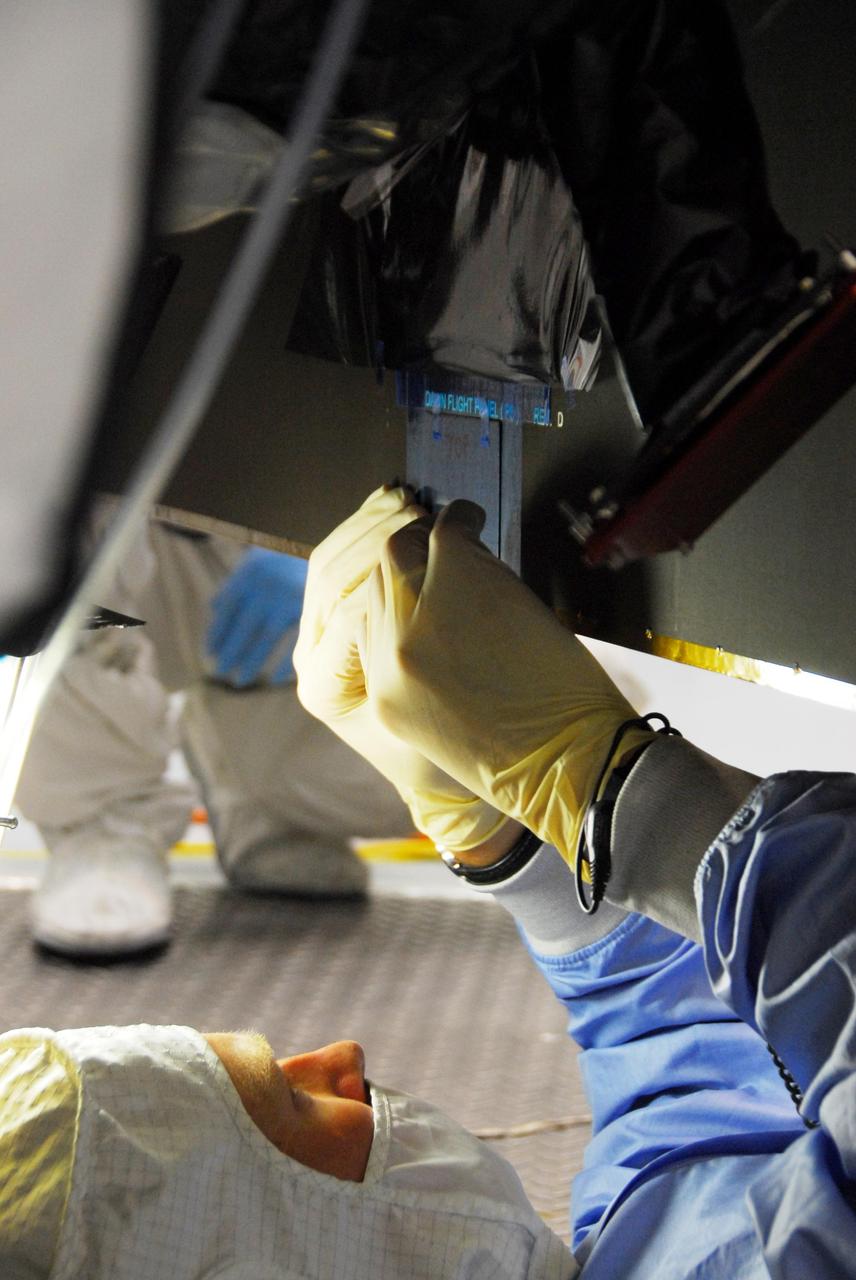 KENNEDY SPACE CENTER, FLA. -- At Astrotech, a Dutch Space technician repairs the damage to the lower edge of the solar array panel on the Dawn spacecraft. On June 11, during a procedure to prepare the Dawn spacecraft for spin-balance testing, the back of a solar array panel was slightly damaged by a technician's tool. The size of the affected area is about 2.5 inches by 2 inches. There is no impact to the launch date of July 7. Dawn's goal is to characterize the conditions and processes of the solar system's earliest epoch 4.5 billion years ago by investigating in detail two of the largest asteroids, Ceres and Vesta. They reside between Mars and Jupiter in the asteroid belt. Photo credit: NASA/George Shelton