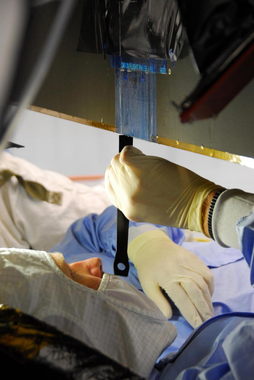 KENNEDY SPACE CENTER, FLA. -- At Astrotech, a Dutch Space technician repairs the damage to the lower edge of the solar array panel on the Dawn spacecraft. On June 11, during a procedure to prepare the Dawn spacecraft for spin-balance testing, the back of a solar array panel was slightly damaged by a technician's tool. The size of the affected area is about 2.5 inches by 2 inches. There is no impact to the launch date of July 7. Dawn's goal is to characterize the conditions and processes of the solar system's earliest epoch 4.5 billion years ago by investigating in detail two of the largest asteroids, Ceres and Vesta. They reside between Mars and Jupiter in the asteroid belt. Photo credit: NASA/George Shelton