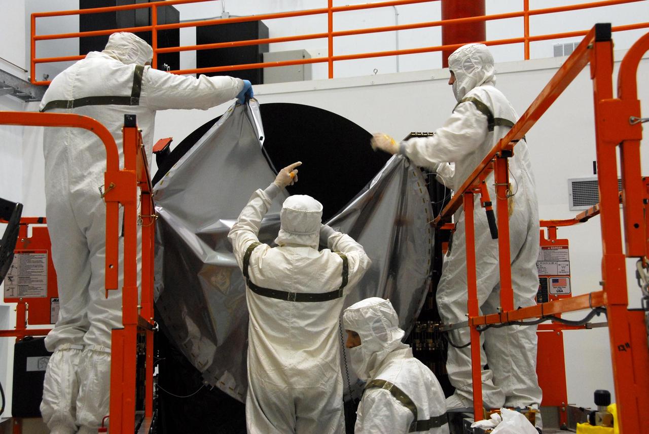 KENNEDY SPACE CENTER, FLA. -- At Astrotech, technicians begin placing the sun shade over the high gain antenna on the Dawn spacecraft. Made of germanium kapton, the shade, which is RF transparent, is placed over the sensitive antenna to reflect and emit harmful solar radiation to prevent the antenna from being excessively heated. Dawn is scheduled to launch July 7 from Pad 17-B on Cape Canaveral Air Force Station. Dawn's goal is to characterize the conditions and processes of the solar system's earliest epoch by investigating in detail the largest protoplanets that have remained intact since their formations: asteroid Vesta and the dwarf planet Ceres. They reside in the extensive zone between Mars and Jupiter together with many other smaller bodies, called the asteroid belt. Photo credit: NASA/George Shelton