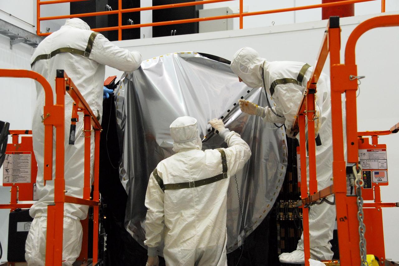 KENNEDY SPACE CENTER, FLA. -- At Astrotech, technicians begin securing the sun shade over the high gain antenna on the Dawn spacecraft. Made of germanium kapton, the shade, which is RF transparent, is placed over the sensitive antenna to reflect and emit harmful solar radiation to prevent the antenna from being excessively heated. Dawn is scheduled to launch July 7 from Pad 17-B on Cape Canaveral Air Force Station. Dawn's goal is to characterize the conditions and processes of the solar system's earliest epoch by investigating in detail the largest protoplanets that have remained intact since their formations: asteroid Vesta and the dwarf planet Ceres. They reside in the extensive zone between Mars and Jupiter together with many other smaller bodies, called the asteroid belt. Photo credit: NASA/George Shelton