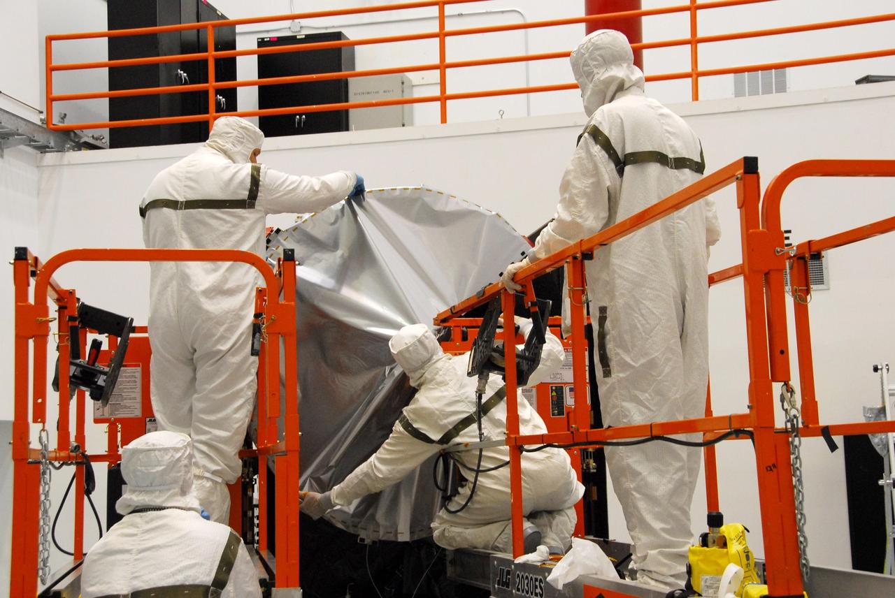 KENNEDY SPACE CENTER, FLA. -- At Astrotech, technicians are securing the sun shade over the high gain antenna on the Dawn spacecraft. Made of germanium kapton, the shade, which is RF transparent, is placed over the sensitive antenna to reflect and emit harmful solar radiation to prevent the antenna from being excessively heated. Dawn is scheduled to launch July 7 from Pad 17-B on Cape Canaveral Air Force Station. Dawn's goal is to characterize the conditions and processes of the solar system's earliest epoch by investigating in detail the largest protoplanets that have remained intact since their formations: asteroid Vesta and the dwarf planet Ceres. They reside in the extensive zone between Mars and Jupiter together with many other smaller bodies, called the asteroid belt. Photo credit: NASA/George Shelton
