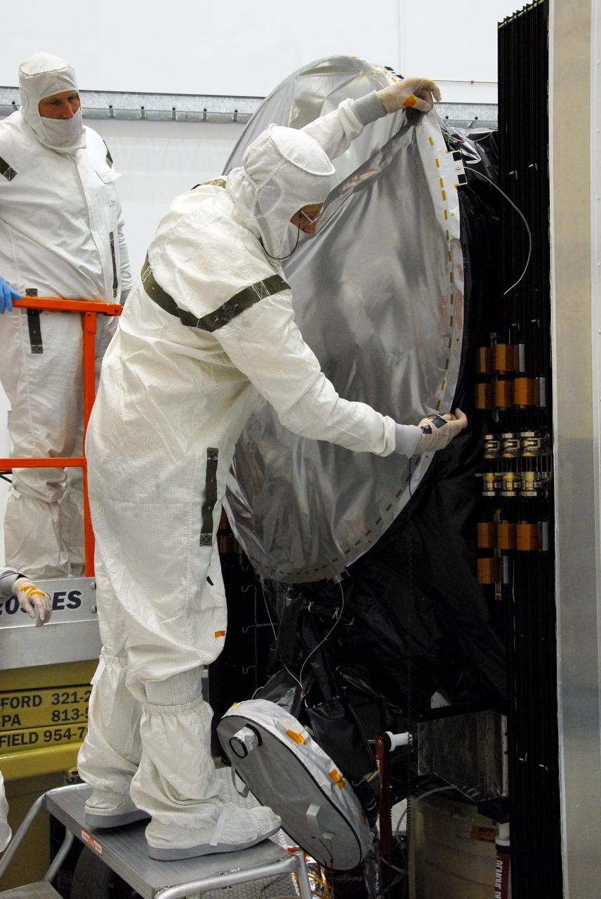 KENNEDY SPACE CENTER, FLA. -- At Astrotech, a technician secures one side of the sun shade over the high gain antenna on the Dawn spacecraft. Made of germanium kapton, the shade, which is RF transparent, is placed over the sensitive antenna to reflect and emit harmful solar radiation to prevent the antenna from being excessively heated. Dawn is scheduled to launch July 7 from Pad 17-B on Cape Canaveral Air Force Station. Dawn's goal is to characterize the conditions and processes of the solar system's earliest epoch by investigating in detail the largest protoplanets that have remained intact since their formations: asteroid Vesta and the dwarf planet Ceres. They reside in the extensive zone between Mars and Jupiter together with many other smaller bodies, called the asteroid belt. Photo credit: NASA/George Shelton