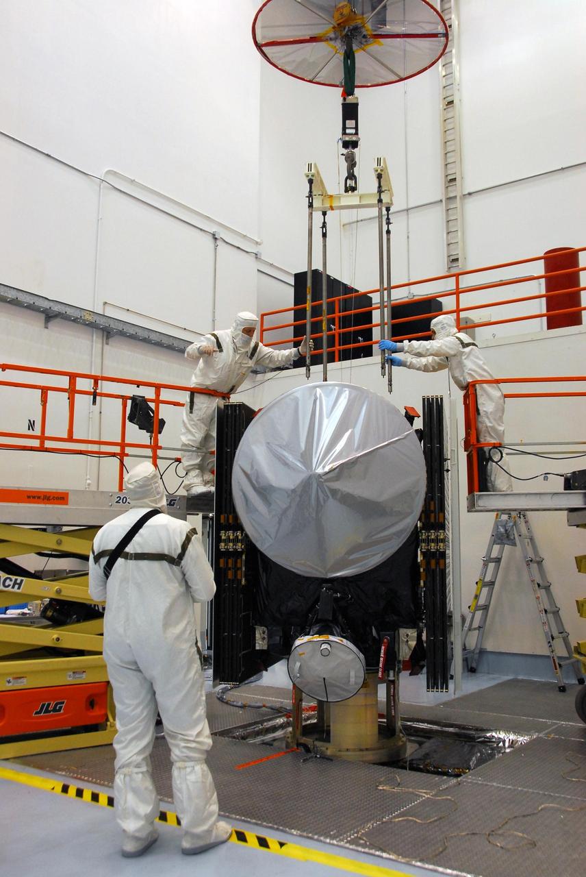 KENNEDY SPACE CENTER, FLA. -- At Astrotech, workers help guide an overhead crane to be attached to the Dawn spacecraft. Dawn will be lifted from its stand, moved and then mated to the upper stage booster for launch. Dawn is scheduled to launch July 7 from Pad 17-B on Cape Canaveral Air Force Station.  Dawn's goal is to characterize the conditions and processes of the solar system's earliest epoch by investigating in detail the largest protoplanets that have remained intact since their formations: asteroid Vesta and the dwarf planet Ceres.  They reside in the extensive zone between Mars and Jupiter together with many other smaller bodies, called the asteroid belt.   Photo credit: NASA/George Shelton