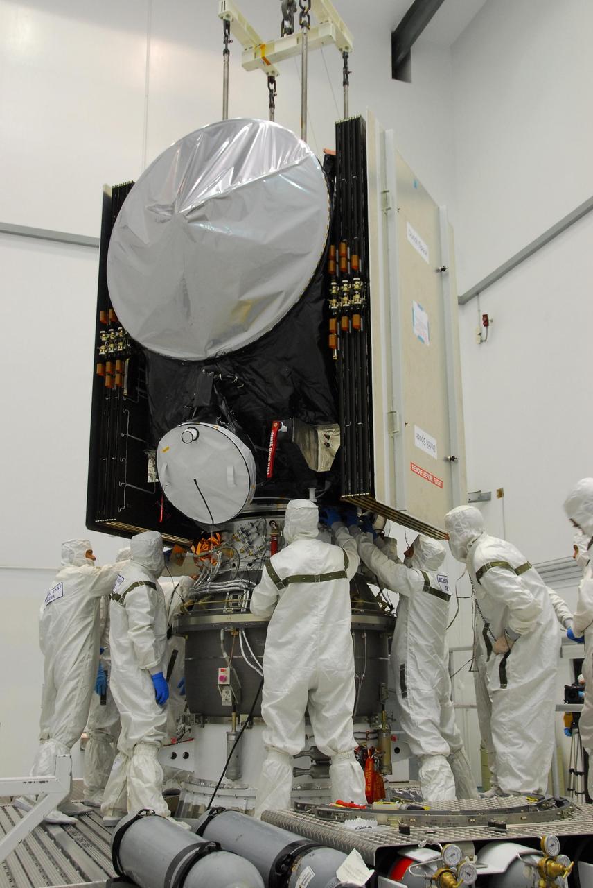 KENNEDY SPACE CENTER, FLA. -- At Astrotech, workers check the attachments of the Dawn spacecraft onto the upper stage booster.   The two elements are being mated for launch.  Dawn's goal is to characterize the conditions and processes of the solar system's earliest epoch by investigating in detail the largest protoplanets that have remained intact since their formations: asteroid Vesta and the dwarf planet Ceres.  They reside in the extensive zone between Mars and Jupiter together with many other smaller bodies, called the asteroid belt.   Photo credit: NASA/George Shelton