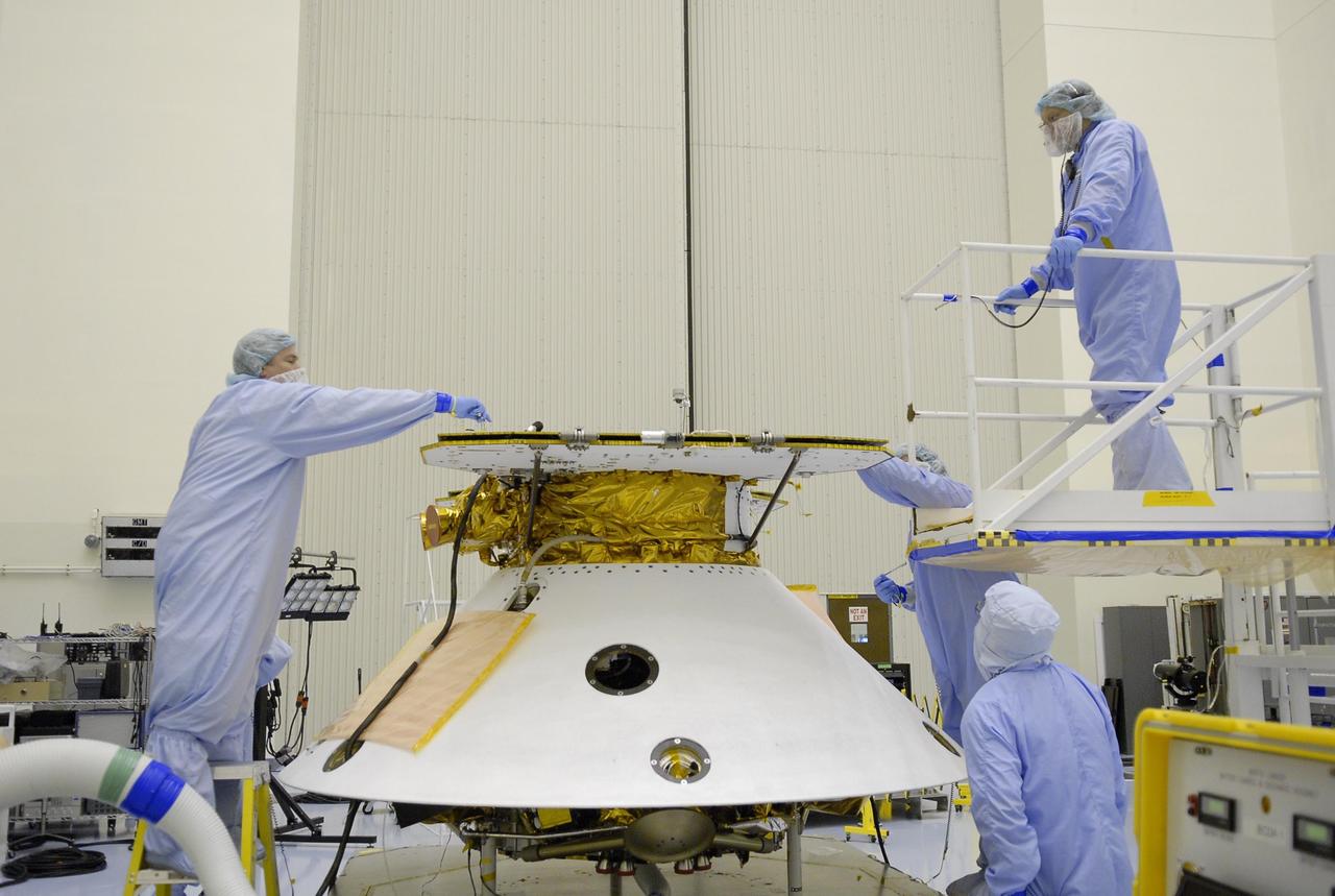 KENNEDY SPACE CENTER, FLA. -- After illumination testing of the solar array panels, technicians complete stowing the panels on the Phoenix Mars Lander spacecraft. The Phoenix will be launched toward Mars to land in icy soils near the planet's north polar permanent ice cap. It will explore the history of the water in these soils and any associated rocks, while monitoring polar climate. Landing on Mars is planned in May 2008 on arctic ground where a mission currently in orbit, Mars Odyssey, has detected high concentrations of ice just beneath the top layer of soil. Phoenix is scheduled to launch Aug. 3 from Pad 17-A at Cape Canaveral Air Force Station . Photo credit: NASA/Kim Shiflett