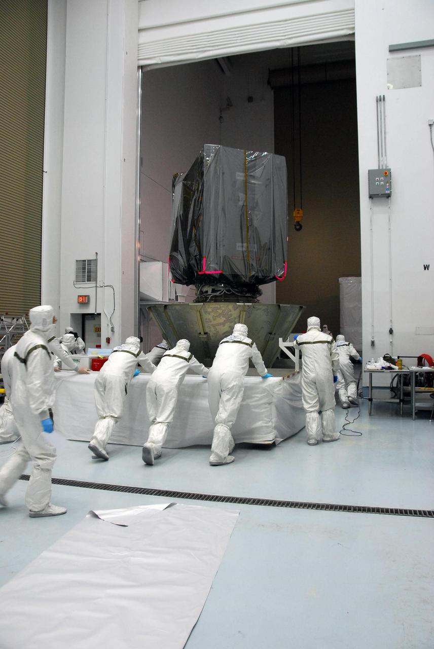KENNEDY SPACE CENTER, FLA. --     At Astrotech, technicians move the partially enclosed Dawn spacecraft into another room to complete the canning.  When enclosed in the canister, Dawn will be transported to Launch Pad 17-B and lifted into the mobile service tower for mating with the Delta II launch vehicle. The Delta II-Heavy, manufactured by the United Launch Alliance, is scheduled to launch the Dawn spacecraft on its 4-year flight to the asteroid belt.  The Delta II-Heavy will use three stages and nine solid-fueled booster rockets to propel Dawn on its way. A 9.5-foot payload fairing will protect the spacecraft from the heat and stresses of launch. Dawn's goal is to characterize the conditions and processes of the solar system's earliest epoch by investigating in detail the largest protoplanets that have remained intact since their formations: asteroid Vesta and the dwarf planet Ceres.  They reside in the extensive zone between Mars and Jupiter together with many other smaller bodies, called the asteroid belt.  Dawn is scheduled to launch July 7.    Photo credit: NASA/George Shelton