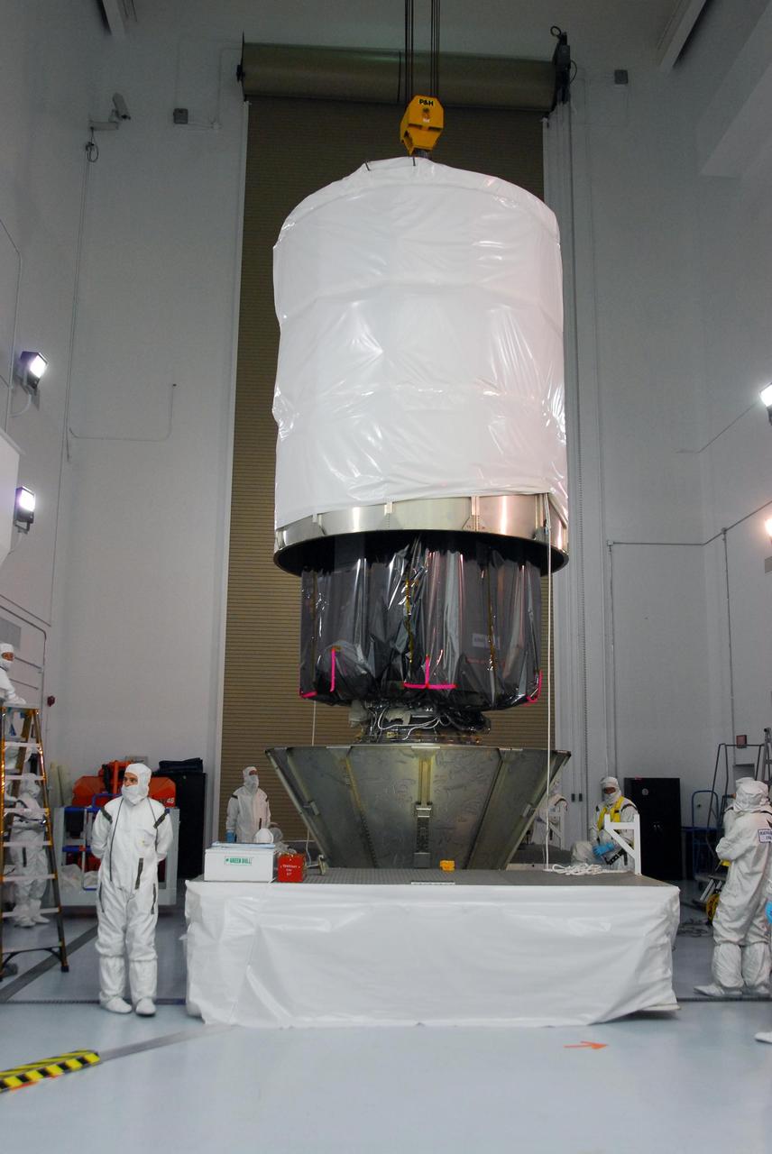 KENNEDY SPACE CENTER, FLA. --    At Astrotech, technicians lower the upper canister over the Dawn spacecraft.  After enclosure, Dawn will be transported to Launch Pad 17-B and lifted into the mobile service tower for mating with the Delta II launch vehicle.  The Delta II-Heavy, manufactured by the United Launch Alliance, is scheduled to launch the Dawn spacecraft on its 4-year flight to the asteroid belt.  The Delta II-Heavy will use three stages and nine solid-fueled booster rockets to propel Dawn on its way. A 9.5-foot payload fairing will protect the spacecraft from the heat and stresses of launch. Dawn's goal is to characterize the conditions and processes of the solar system's earliest epoch by investigating in detail the largest protoplanets that have remained intact since their formations: asteroid Vesta and the dwarf planet Ceres.  They reside in the extensive zone between Mars and Jupiter together with many other smaller bodies, called the asteroid belt.  Dawn is scheduled to launch July 7.    Photo credit: NASA/George Shelton