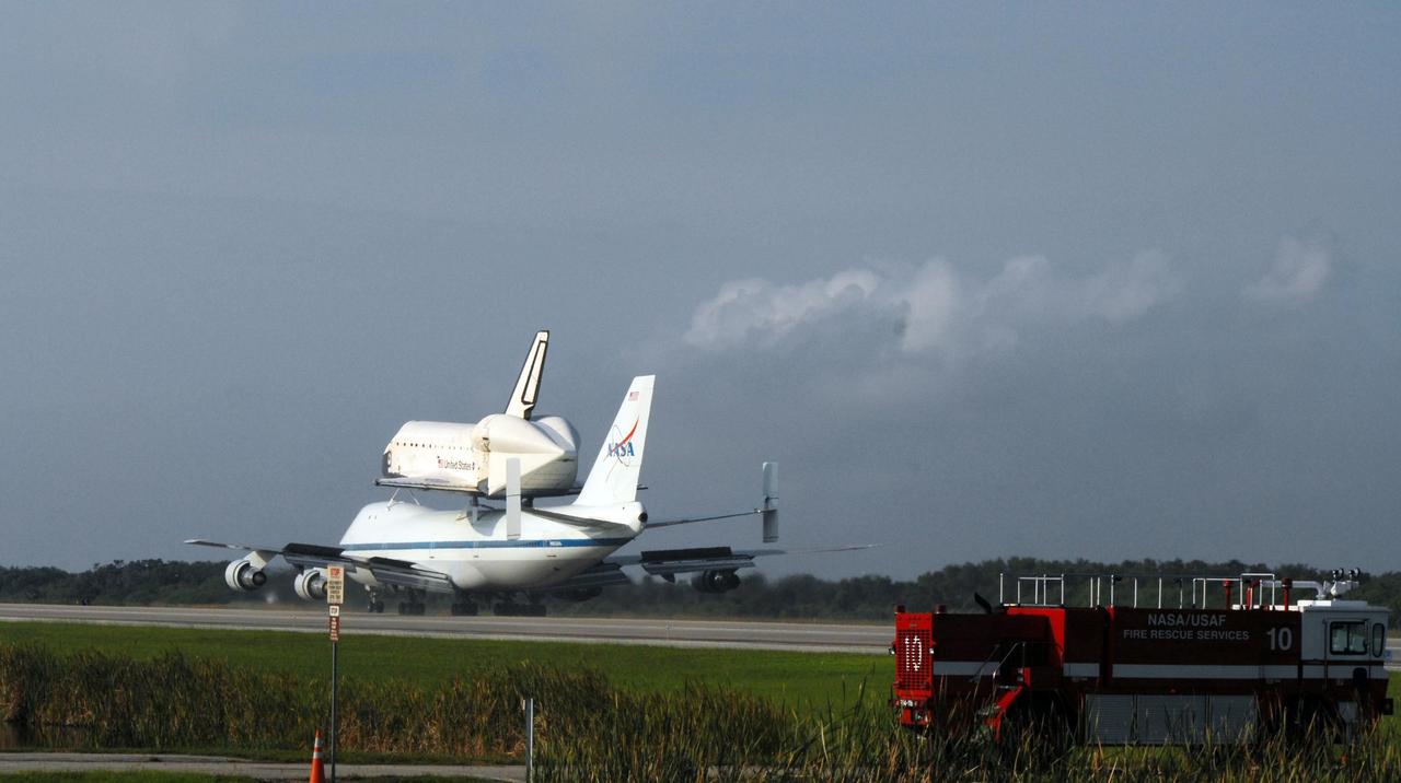 KENNEDY SPACE CENTER, FLA. -- After a three-day trip from California, the shuttle carrier aircraft, or SCA, and its piggyback passenger Atlantis taxi down the KSC Shuttle Landing Facility runway after landing. Touchdown was at 8:27 a.m. EDT. The SCA is a modified Boeing 747 jetliner. Visible on Atlantis is the tail cone that covers and protects the main engines during the ferry flight. Atlantis landed at Edwards Air Force Base in California to end mission STS-117. The return to KSC began July 1 and took three days after stops across the country for fuel. The last stop was at Ft. Campbell in Kentucky. Weather conditions over the last leg postponed the return trip until July 3. Atlantis will be removed from the back of the SCA via the mate/demate device at the SLF. It will then be towed to the Orbiter Processing Facility to begin processing for its next launch, mission STS-122 in December. Photo credit: NASA/Ken Thornsley