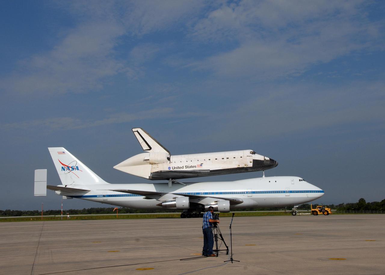 KENNEDY SPACE CENTER, FLA. -- The shuttle carrier aircraft, or SCA, and its piggyback passenger Atlantis are towed across the Shuttle Landing Facility after their landing. Touchdown was at 8:27 a.m. EDT. The SCA is a modified Boeing 747 jetliner. Visible on Atlantis is the tail cone that covers and protects the main engines during the ferry flight. Atlantis landed at Edwards Air Force Base in California to end mission STS-117. The return to KSC began July 1 and took three days after stops across the country for fuel. The last stop was at Ft. Campbell in Kentucky. Weather conditions over the last leg postponed the return trip until July 3. Atlantis will be removed from the back of the SCA via the mate/demate device at the SLF. It will then be towed to the Orbiter Processing Facility to begin processing for its next launch, mission STS-122 in December. Photo credit: NASA/Ken Thornsley