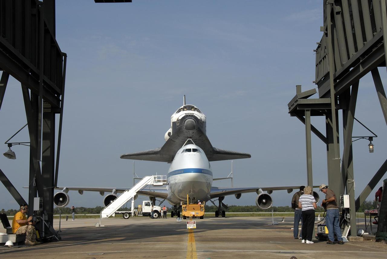 KENNEDY SPACE CENTER, FLA. -- The shuttle carrier aircraft, or SCA, and its piggyback passenger Atlantis are poised to be towed into the mate/demate device, in the foreground. The device will lift the orbiter and put it back on the ground. After a three-day, cross-country trip, the orbiter/SCA duo touched down at 8:27 a.m. EDT. The SCA is a modified Boeing 747 jetliner. Atlantis landed at Edwards Air Force Base in California to end mission STS-117. The return to KSC began July 1 and included several stops across the country for fuel. The last stop was at Ft. Campbell in Kentucky. Weather conditions over the last leg postponed the return trip until July 3. After demate, Atlantis will then be towed to the Orbiter Processing Facility to begin processing for its next launch, mission STS-122 in December. Photo credit: NASA/Kim Shiflett