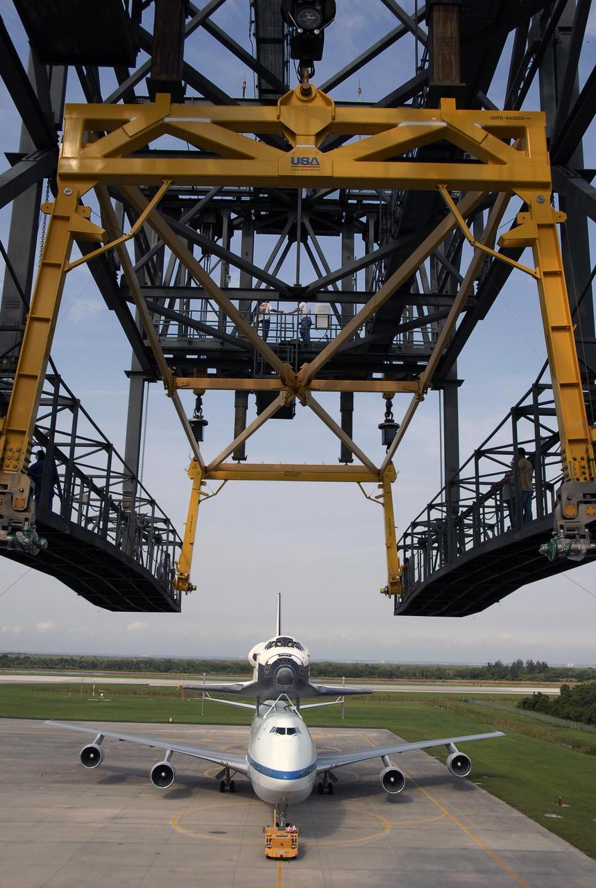 KENNEDY SPACE CENTER, FLA. --  On the KSC Shuttle Landing Facility, the shuttle carrier aircraft, or SCA, with the orbiter Atlantis on its back is towed toward the mate/demate device (upper foreground).  Under the device, the orbiter will be detached from the SCA and lowered onto a transporter.  Then Atlantis will be towed to the Orbiter Processing Facility to begin processing for its next launch, mission STS-122 in December.  Atlantis landed at Edwards Air Force Base in California on June 22 to end mission STS-117.  It returned to Kennedy atop the SCA on July 3 after a three-day, cross-country flight due to fuel stops and weather delays. Touchdown was at 8:27 a.m. EDT. Photo credit: NASA/Kim Shiflett