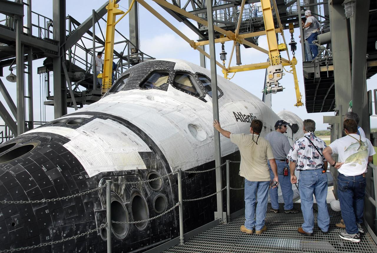 KENNEDY SPACE CENTER, FLA. -- On the KSC Shuttle Landing Facility, workers supervise the movement of the sling above the orbiter Atlantis. The sling will be attached and lift the orbiter away from the shuttle carrier aircraft (SCA) underneath. The SCA carried the orbiter piggyback from California. Atlantis landed at Edwards Air Force Base in California on June 22 to end mission STS-117. It returned to Kennedy atop the SCA on July 3 after a three-day, cross-country flight due to fuel stops and weather delays. Touchdown was at 8:27 a.m. EDT. Photo credit: NASA/Kim Shiflett
