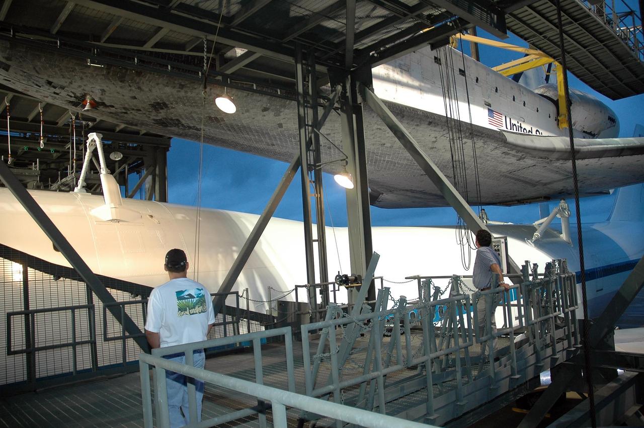 KENNEDY SPACE CENTER, FLA. -- On the mate/demate device at Kennedy Space Center's Shuttle Landing Facility, technicians monitor the progress as Atlantis is lifted up from the shuttle carrier aircraft, or SCA, beneath it. The orbiter will be lowered to the ground and then towed to the Orbiter Processing Facility to begin processing for its next launch, mission STS-122 in December. Atlantis arrived at Kennedy Space Center atop the SCA on July 3 after a three-day, cross-country flight due to fuel stops and weather delays. Touchdown was at 8:27 a.m. EDT. Atlantis landed at Edwards Air Force Base in California on June 22 to end mission STS-117. Photo credit: NASA/Jack Pfaller.