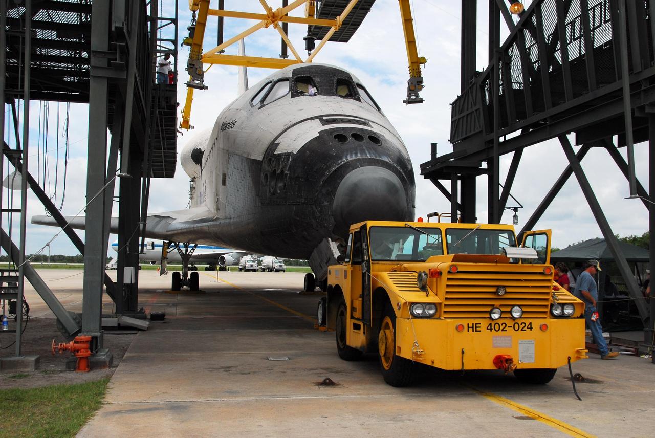 KENNEDY SPACE CENTER, FLA. -- Workers use an aircraft tug vehicle to back Atlantis away from the mate/demate device at Kennedy Space Center's Shuttle Landing Facility. The orbiter will be towed to the Orbiter Processing Facility where processing will begin for its next launch, mission STS-122 in December. Atlantis arrived at Kennedy Space Center atop the SCA on July 3 after a three-day, cross-country flight due to fuel stops and weather delays. Touchdown was at 8:27 a.m. EDT. Atlantis landed at Edwards Air Force Base in California on June 22 to end mission STS-117. Photo credit: NASA/George Shelton.