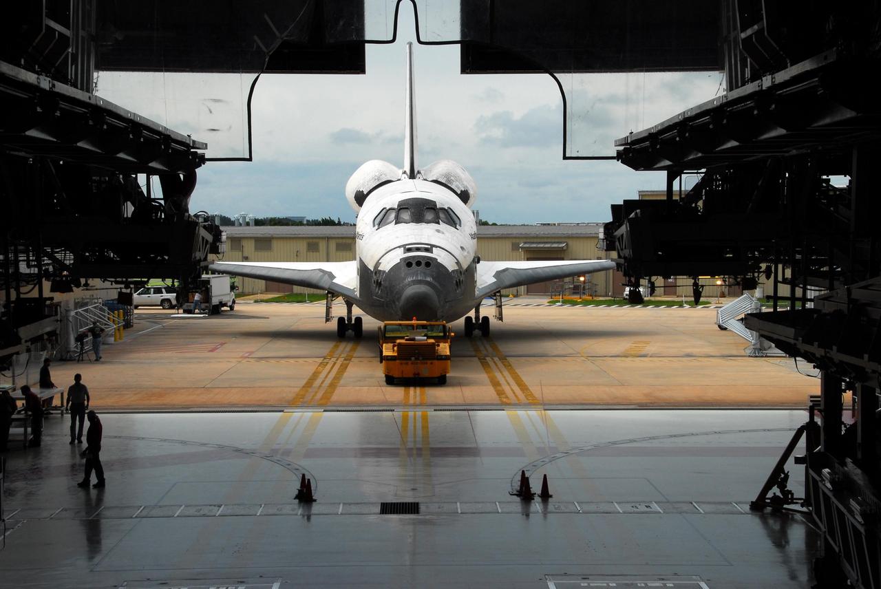KENNEDY SPACE CENTER, FLA. -- Framed by work platforms inside the Orbiter Processing Facility, Atlantis is towed toward the entrance to the facility. The orbiter will undergo processing for its next launch, mission STS-122 in December. Atlantis arrived at Kennedy Space Center atop the SCA on July 3 after a three-day, cross-country flight due to fuel stops and weather delays. Touchdown was at 8:27 a.m. EDT. Atlantis landed at Edwards Air Force Base in California on June 22 to end mission STS-117. Photo credit: NASA/George Shelton.
