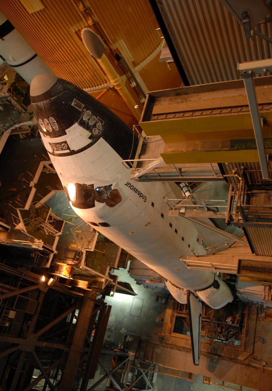 KENNEDY SPACE CENTER, FLA. --   Space Shuttle Endeavour is viewed from a high level in the Vehicle Assembly Building.  Lights from above cast an orange glow.  Visible behind Endeavour are the orange external tank and one of the white solid rocket boosters on the left. The many platform levels on either side of the shuttle provide access for work.  The shuttle assembly rests on the mobile launcher platform, which will be lifted by the crawler-transporter for the slow journey to the pad.  Rollout was originally planned for just after midnight on July 10 but the move was canceled by NASA managers because unfavorable weather was predicted to arrive in the launch area before the vehicle would be secured at the pad.   Rollout is scheduled to begin again about 9 p.m. July 10.  Photo credit: NASA/Ken Thornsley