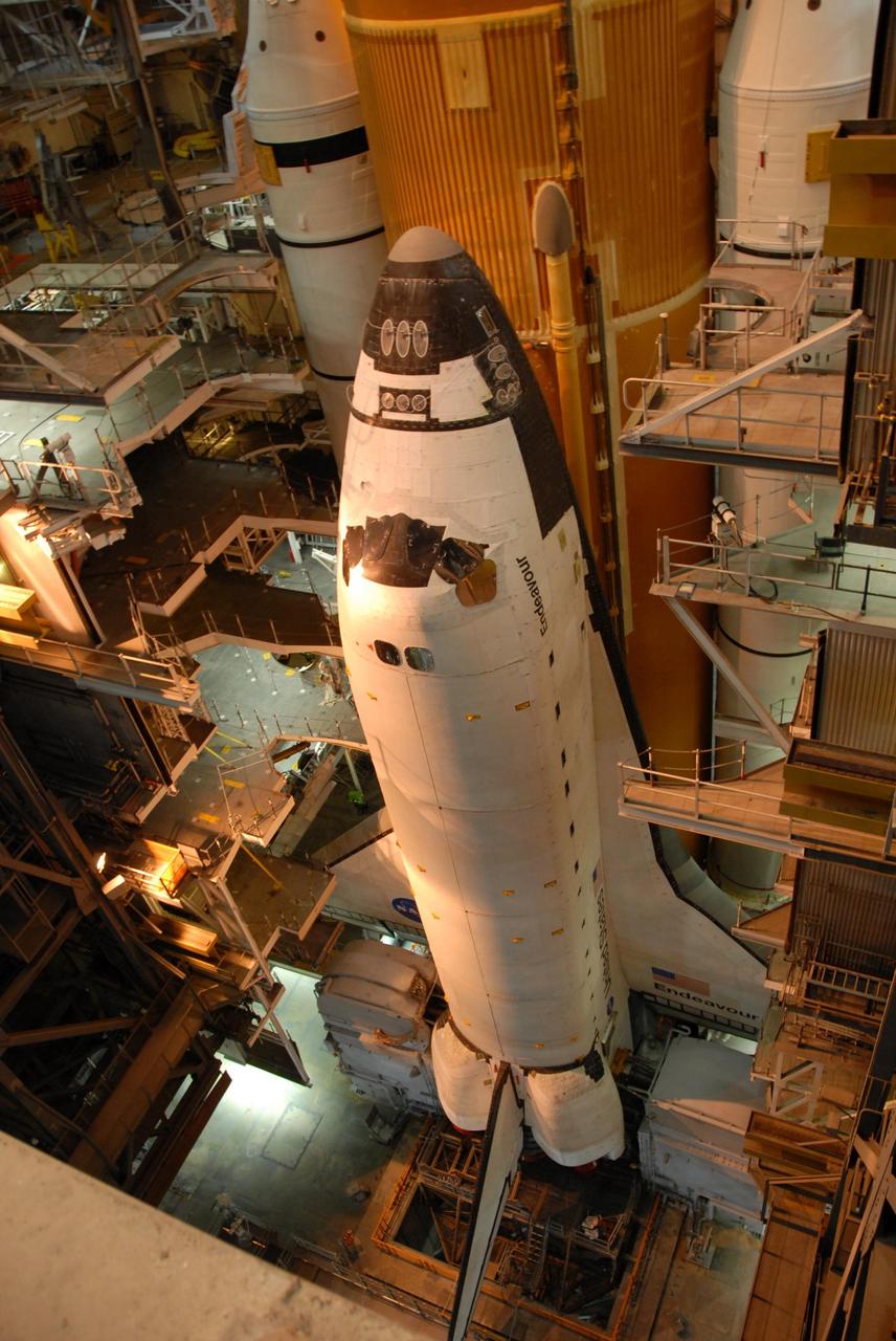 KENNEDY SPACE CENTER, FLA. --   Space Shuttle Endeavour is viewed from a high level in the Vehicle Assembly Building.  Lights from above cast an orange glow.  Visible behind Endeavour are the orange external tank and the white solid rocket boosters on either side.  The many platform levels on either side of the shuttle provide access for work. The shuttle assembly rests on the mobile launcher platform, which will be lifted by the crawler-transporter for the slow journey to the pad. Rollout was originally planned for just after midnight on July 10 but the move was canceled by NASA managers because unfavorable weather was predicted to arrive in the launch area before the vehicle would be secured at the pad.   Rollout is scheduled to begin again about 9 p.m. July 10.  Photo credit: NASA/Ken Thornsley