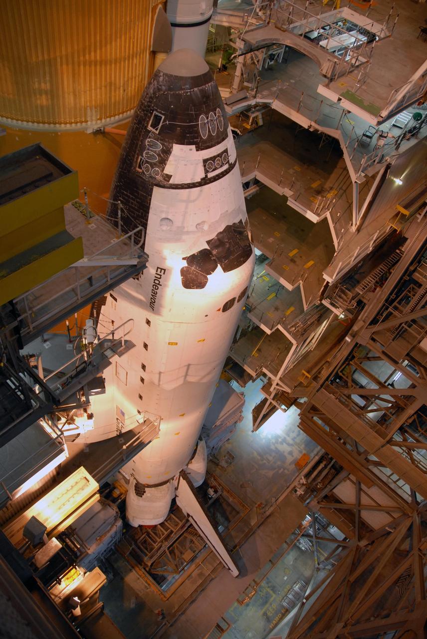 KENNEDY SPACE CENTER, FLA. --   Space Shuttle Endeavour is viewed from a high level in the Vehicle Assembly Building.  Lights from above cast an orange glow.  Visible behind Endeavour, at left, are the orange external tank and the white solid rocket boosters on either side.  The many platform levels on either side of the shuttle provide access for work.  The shuttle assembly rests on the mobile launcher platform, which will be lifted by the crawler-transporter for the slow journey to the pad.  Rollout was originally planned for just after midnight on July 10 but the move was canceled by NASA managers because unfavorable weather was predicted to arrive in the launch area before the vehicle would be secured at the pad.   Rollout is scheduled to begin again about 9 p.m. July 10.  Photo credit: NASA/Ken Thornsley