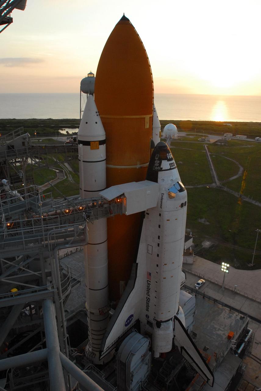 KENNEDY SPACE CENTER, FLA. -- The dawn sky over the Atlantic Ocean reveals Space Shuttle Endeavour sitting on Launch Pad 39A. First motion out of the Vehicle Assembly Building was at 8:10 p.m. July 10, and the shuttle was hard down on the pad at 3:02 a.m. July 11. The orbiter access arm is already extended to the orbiter from the fixed service structure. Peering just above the solid rocket booster on the left is the 290-foot-tall water tank. It provides the deluge over the mobile launcher platform for sound suppression during liftoff. Endeavour is scheduled to launch on mission STS-118 on Aug. 7. During the mission, Endeavour will carry into orbit the S5 truss, SPACEHAB module and external stowage platform 3. The mission is the 22nd flight to the International Space Station and will mark the first flight of Mission Specialist Barbara Morgan, the teacher-turned-astronaut whose association with NASA began more than 20 years ago. STS-118 will be the first flight since 2002 for Endeavour, which has undergone extensive modifications, including the addition of safety upgrades already added to orbiters Discovery and Atlantis. Photo credit: NASA/George Shelton