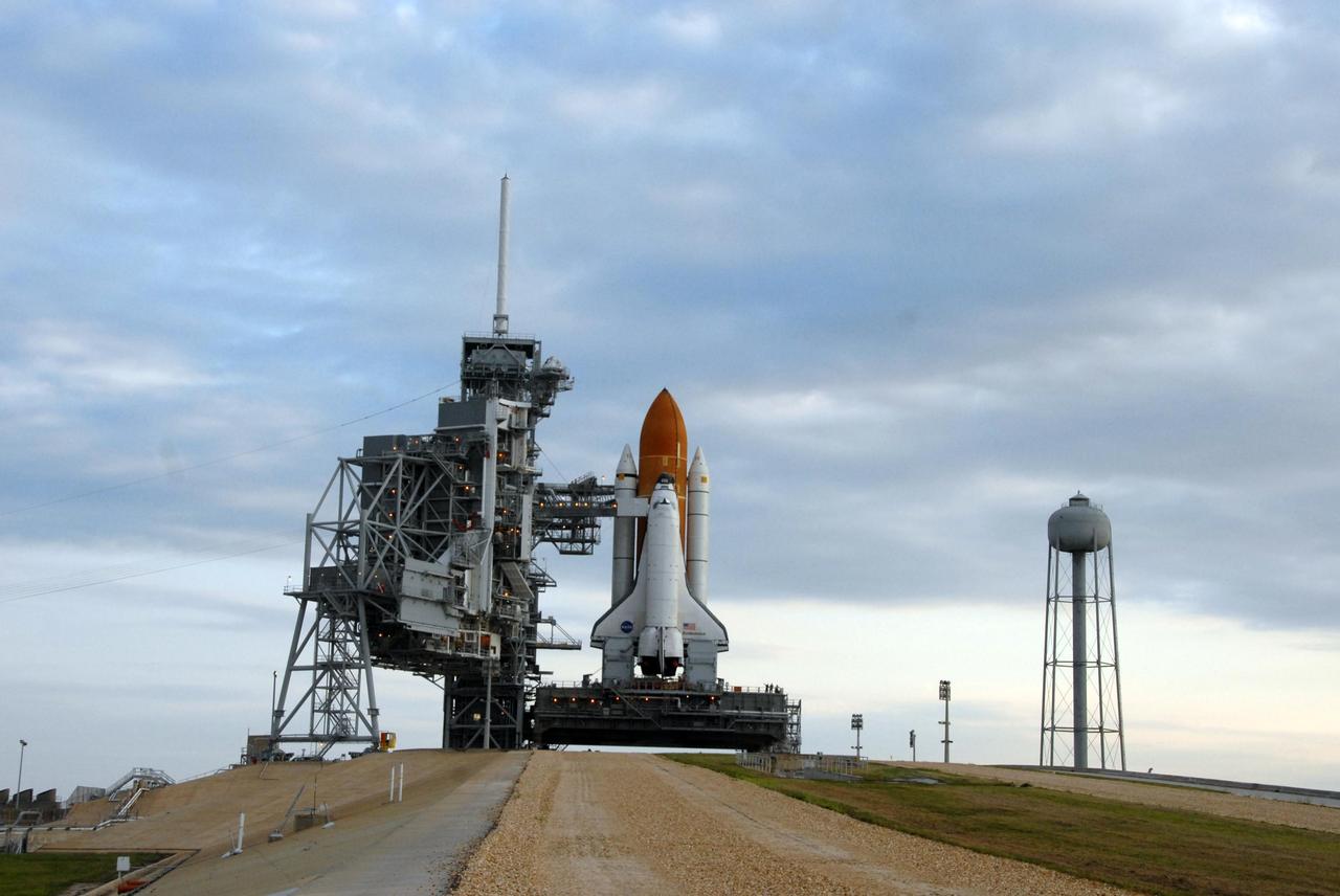 KENNEDY SPACE CENTER, FLA. - Space Shuttle Endeavour rests on Launch Pad 39A after rolling out from the Vehicle Assembly Building over night. First motion out of the VAB was at 8:10 p.m. July 10, and the shuttle was hard down on the pad at 3:02 a.m. July 11. The shuttle sits on top of the mobile launcher platform. At far left is the rotating service structure, which can be rolled around to enclose the shuttle for access during processing. Behind it is the fixed service structure, topped by an 80-foot-tall lightning mast. At right is the 290-foot-tall water tank, which provides the deluge over the mobile launcher platform for sound suppression during liftoff. Endeavour is scheduled to launch on mission STS-118 on Aug. 7. During the mission, Endeavour will carry into orbit the S5 truss, SPACEHAB module and external stowage platform 3. The mission is the 22nd flight to the International Space Station and will mark the first flight of Mission Specialist Barbara Morgan, the teacher-turned-astronaut whose association with NASA began more than 20 years ago. STS-118 will be the first flight since 2002 for Endeavour, which has undergone extensive modifications, including the addition of safety upgrades already added to orbiters Discovery and Atlantis. Photo credit: NASA/Ken Thornsley