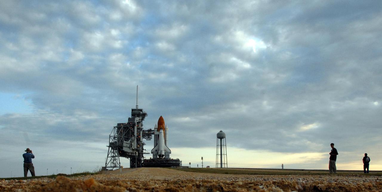 KENNEDY SPACE CENTER, FLA. - Around Launch Pad 39A, photographers pick their spot to snap shots of Space Shuttle Endeavour, which rolled to the pad over night. First motion out of the Vehicle Assembly Building was at 8:10 p.m. July 10, and the shuttle was hard down on the pad at 3:02 a.m. July 11. At far left is the rotating service structure, which can be rolled around to enclose the shuttle for access during processing. Barely visible behind it is the fixed service structure, topped by an 80-foot-tall lightning mast. At right is the 290-foot-tall water tank, which provides the deluge over the mobile launcher platform for sound suppression during liftoff. The proximity of the water and brush and grass signify the close relationship of Kennedy Space Center and the Merritt Island National Wildlife Center, which surrounds it. Endeavour is scheduled to launch on mission STS-118 on Aug. 7. During the mission, Endeavour will carry into orbit the S5 truss, SPACEHAB module and external stowage platform 3. The mission is the 22nd flight to the International Space Station and will mark the first flight of Mission Specialist Barbara Morgan, the teacher-turned-astronaut whose association with NASA began more than 20 years ago. STS-118 will be the first flight since 2002 for Endeavour, which has undergone extensive modifications, including the addition of safety upgrades already added to orbiters Discovery and Atlantis. Photo credit: NASA/Ken Thornsley