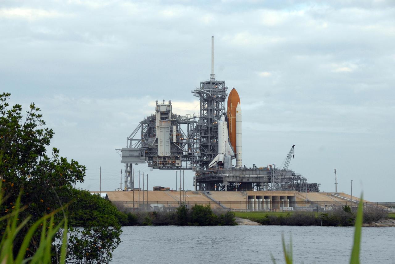 KENNEDY SPACE CENTER, FLA. - Sandwiched between gray clouds and the Banana Creek can be seen Space Shuttle Endeavour on Launch Pad 39A. The shuttle rolled to the pad overnight to get ready for liftoff on mission STS-118. First motion out of the Vehicle Assembly Building was at 8:10 p.m. July 10, and the shuttle was hard down on the pad at 3:02 a.m. July 11. At far left is the rotating service structure, which can be rolled around to enclose the shuttle for access during processing. The proximity of the water and brush and grass signify the close relationship of Kennedy Space Center and the Merritt Island National Wildlife Center, which surrounds it. Endeavour is scheduled to launch on mission STS-118 on Aug. 7. During the mission, Endeavour will carry into orbit the S5 truss, SPACEHAB module and external stowage platform 3. The mission is the 22nd flight to the International Space Station and will mark the first flight of Mission Specialist Barbara Morgan, the teacher-turned-astronaut whose association with NASA began more than 20 years ago. STS-118 will be the first flight since 2002 for Endeavour, which has undergone extensive modifications, including the addition of safety upgrades already added to orbiters Discovery and Atlantis. Photo credit: NASA/Ken Thornsley