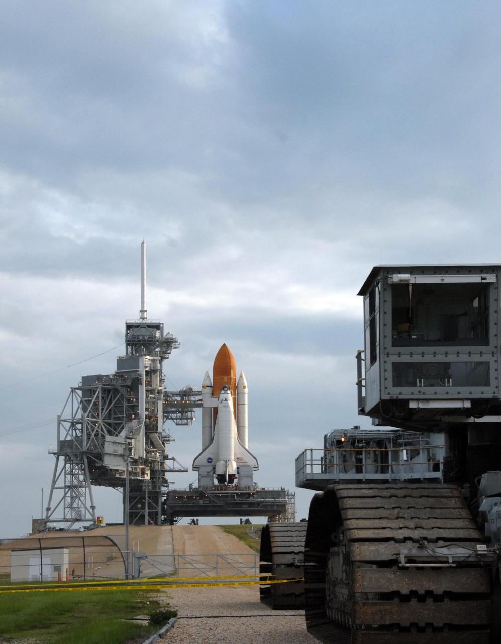 KENNEDY SPACE CENTER, FLA. - At right, the crawler-transporter rolls away from Launch Pad 39A after delivering Space Shuttle Endeavour, in the background. Rollout of the shuttle began at 8:10 p.m. July 10 and concluded at 3:02 a.m. July 11. At far left is the rotating service structure, which can be rolled around to enclose the shuttle for access during processing. Behind it is the fixed service structure, topped by an 80-foot-tall lightning mast. Extending from it is the orbiter access arm, which provides access into the vehicle. Endeavour is scheduled to launch on mission STS-118 on Aug. 7. During the mission, Endeavour will carry into orbit the S5 truss, SPACEHAB module and external stowage platform 3. The mission is the 22nd flight to the International Space Station and will mark the first flight of Mission Specialist Barbara Morgan, the teacher-turned-astronaut whose association with NASA began more than 20 years ago. STS-118 will be the first flight since 2002 for Endeavour, which has undergone extensive modifications, including the addition of safety upgrades already added to orbiters Discovery and Atlantis. Photo credit: NASA/Ken Thornsley