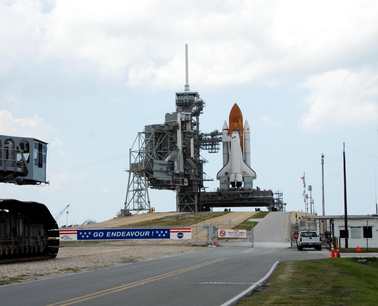 KENNEDY SPACE CENTER, FLA. - At left, the edge of the crawler-transporter is seen rolling away from Launch Pad 39A after delivering Space Shuttle Endeavour, in the background. Rollout of the shuttle began at 8:10 p.m. July 10 and concluded at 3:02 a.m. July 11. To the left of the shuttle is the rotating service structure, which can be rolled around to enclose the vehicle for access during processing. Behind it is the fixed service structure, topped by an 80-foot-tall lightning mast. Extending from it to Endeavour is the orbiter access arm, which provides access into the vehicle. Endeavour is scheduled to launch on mission STS-118 on Aug. 7. During the mission, Endeavour will carry into orbit the S5 truss, SPACEHAB module and external stowage platform 3. The mission is the 22nd flight to the International Space Station and will mark the first flight of Mission Specialist Barbara Morgan, the teacher-turned-astronaut whose association with NASA began more than 20 years ago. STS-118 will be the first flight since 2002 for Endeavour, which has undergone extensive modifications, including the addition of safety upgrades already added to orbiters Discovery and Atlantis. Photo credit: NASA/Ken Thornsley