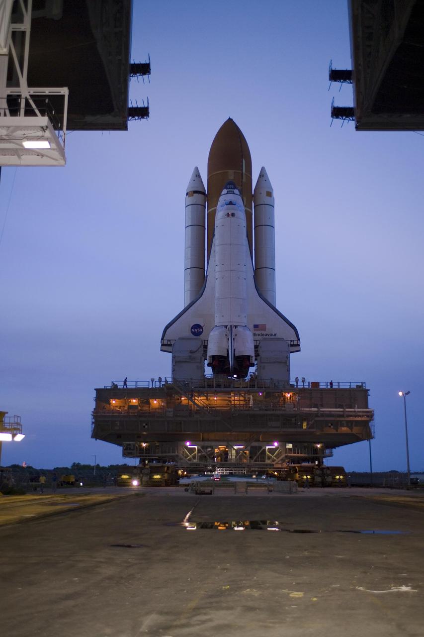KENNEDY SPACE CENTER, FLA. -- At sunset, Space Shuttle Endeavour, atop the lighted mobile launcher platform, exits the Vehicle Assembly Building for rollout to Launch Pad 39A. First motion out of the VAB was at 8:10 p.m. July 10, and the shuttle was hard down on the pad at 3:02 a.m. July 11. Seen below the orbiter's wings and attached to the launcher platform are the tail masts, which provide several umbilical connections to the orbiter, including a liquid-oxygen line through one and a liquid-hydrogen line through another. The shuttle and platform are being carried by the crawler-transporter. The trip will take between six and eight hours. Endeavour is scheduled to launch on mission STS-118 on Aug. 7. During the mission, Endeavour will carry into orbit the S5 truss, SPACEHAB module and external stowage platform 3. The mission is the 22nd flight to the International Space Station and will mark the first flight of Mission Specialist Barbara Morgan, the teacher-turned-astronaut whose association with NASA began more than 20 years ago. STS-118 will be the first flight since 2002 for Endeavour, which has undergone extensive modifications, including the addition of safety upgrades already added to orbiters Discovery and Atlantis. Photo credit: NASA/Tom Farrar