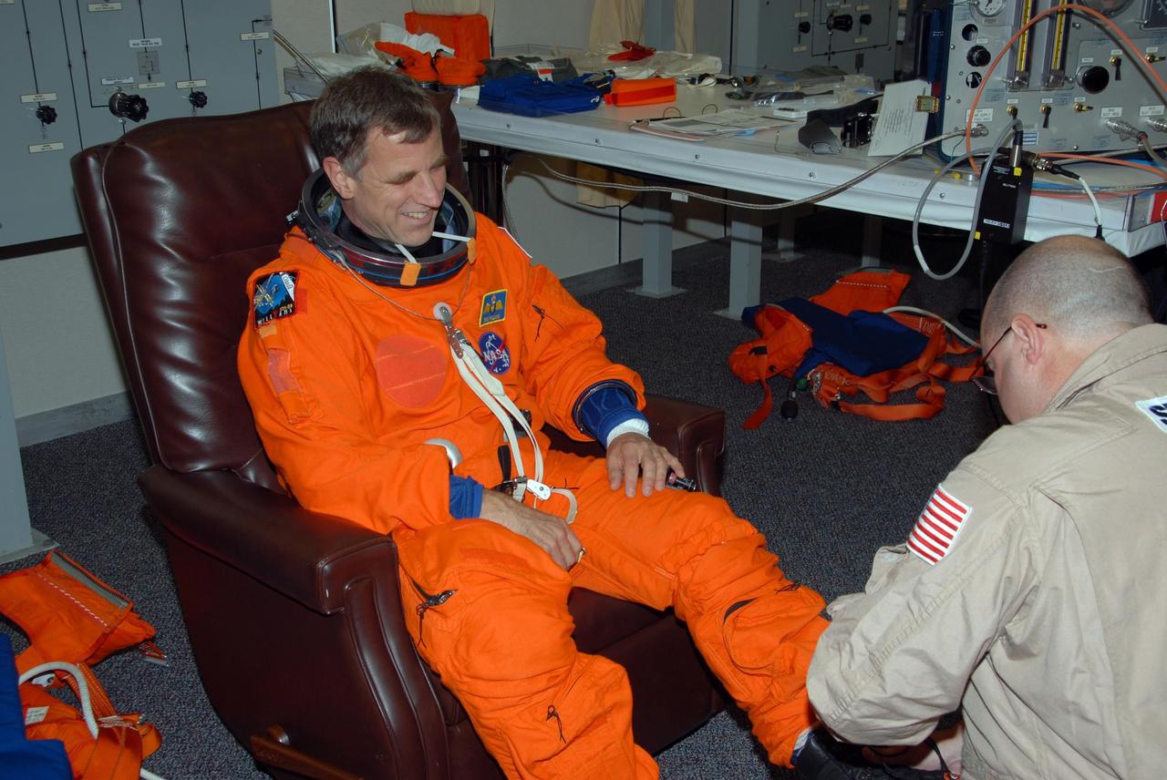KENNEDY SPACE CENTER, Fla. -- STS-118 Mission Specialist Dave Williams gets help with his boot during fit testing of his launch and entry suit. He and other crew members are at Kennedy for the Terminal Countdown Demonstration Test (TCDT) activities, a dress rehearsal for launch. TCDT activities include the M-113 training, payload familiarization, emergency egress training at the pad and a simulated launch countdown. The STS-118 payload aboard Space Shuttle Endeavour includes the S5 truss, a SPACEHAB module and external stowage platform 3. The mission is the 22nd flight to the International Space Station and is targeted for launch on Aug. 7. NASA/George Shelton