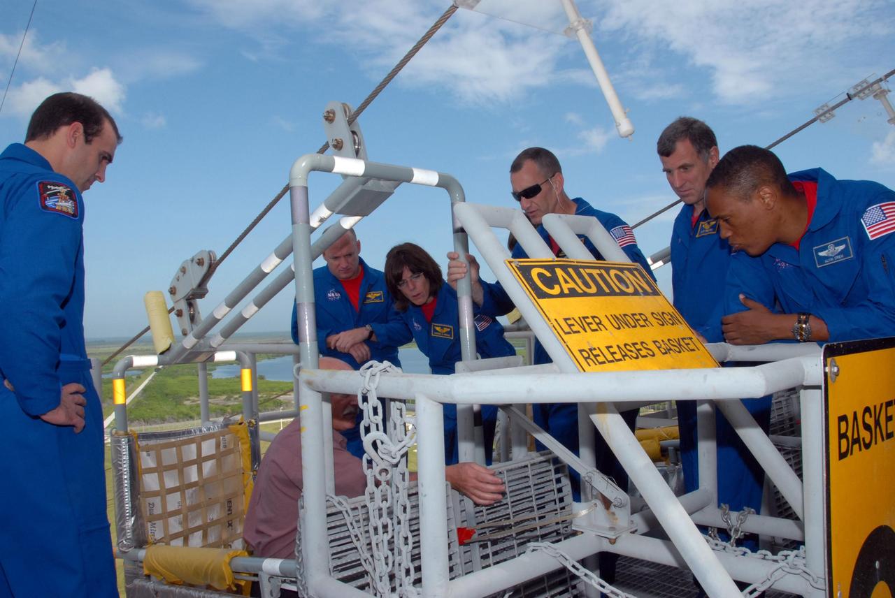 KENNEDY SPACE CENTER, Fla.  --  On an upper level of the Pad 39A fixed service structure, the STS-118 crew members get directions about using the slidewire basket that is part of the emergency egress system.  At left is Mission Specialist Rick Mastracchio.  At right are (from the left) Commander Scott Kelly, Mission Specialist Barbara R. Morgan, Pilot Charlie Hobaugh and Mission Specialists Dave Williams and Alvin Drew. Morgan joined NASA's Teacher in Space program in 1985 and was selected as an astronaut in 1998. Williams represents the Canadian Space Agency. The crew is at Kennedy for training activities in the terminal countdown demonstration test, or TCDT.  TCDT activities include M-113 training, payload familiarization, the emergency egress training at the pad and a simulated launch countdown.  The mission is the 22nd flight to the International Space Station and Space Shuttle Endeavour will carry a payload including the S5 truss, a SPACEHAB module and external stowage platform 3. STS-118 is targeted for launch on Aug. 7.  NASA/George Shelton